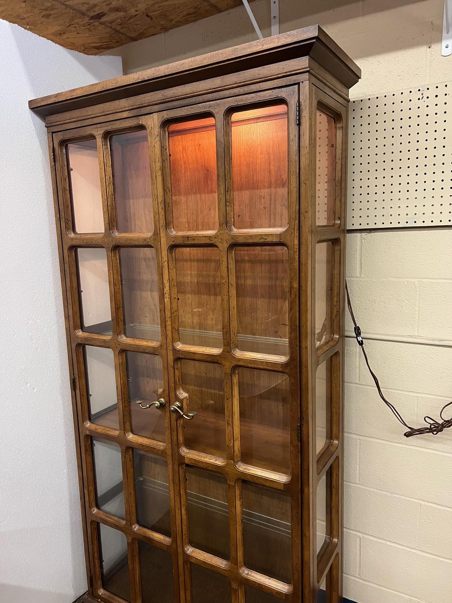 Walnut china display curio cabinet by Drexel. Stamped at the back. Lights at the top and bottom. Top light works. Bottom lights do not currently work. 
Featuring three removable glass shelves and one fixed wood shelf. Minor signs of wear.