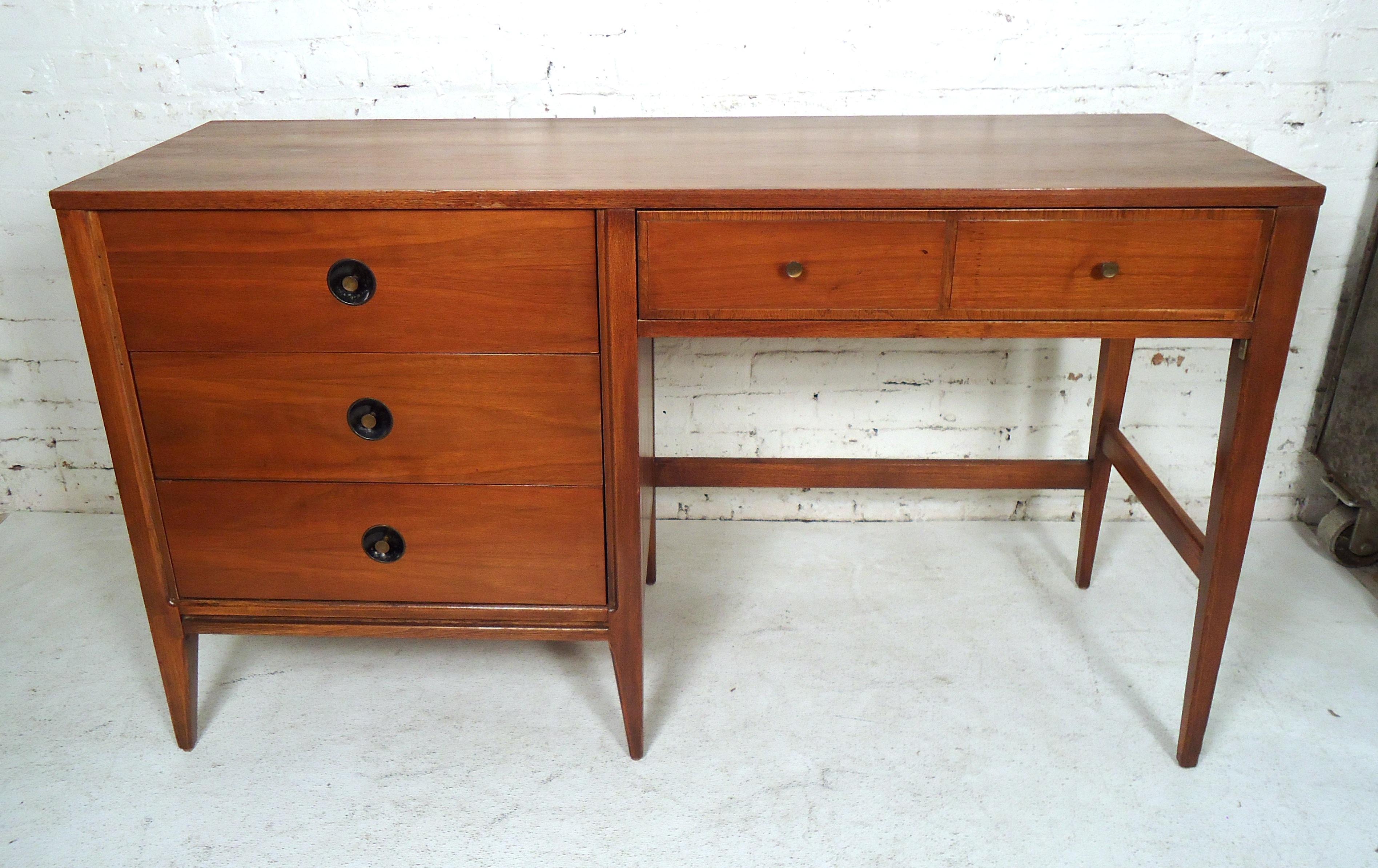 Sleek vintage modern desk featuring rich walnut wood grain, four drawers, unique pulls, and a sturdy frame.
(Please confirm item location - NY or NJ - with dealer).