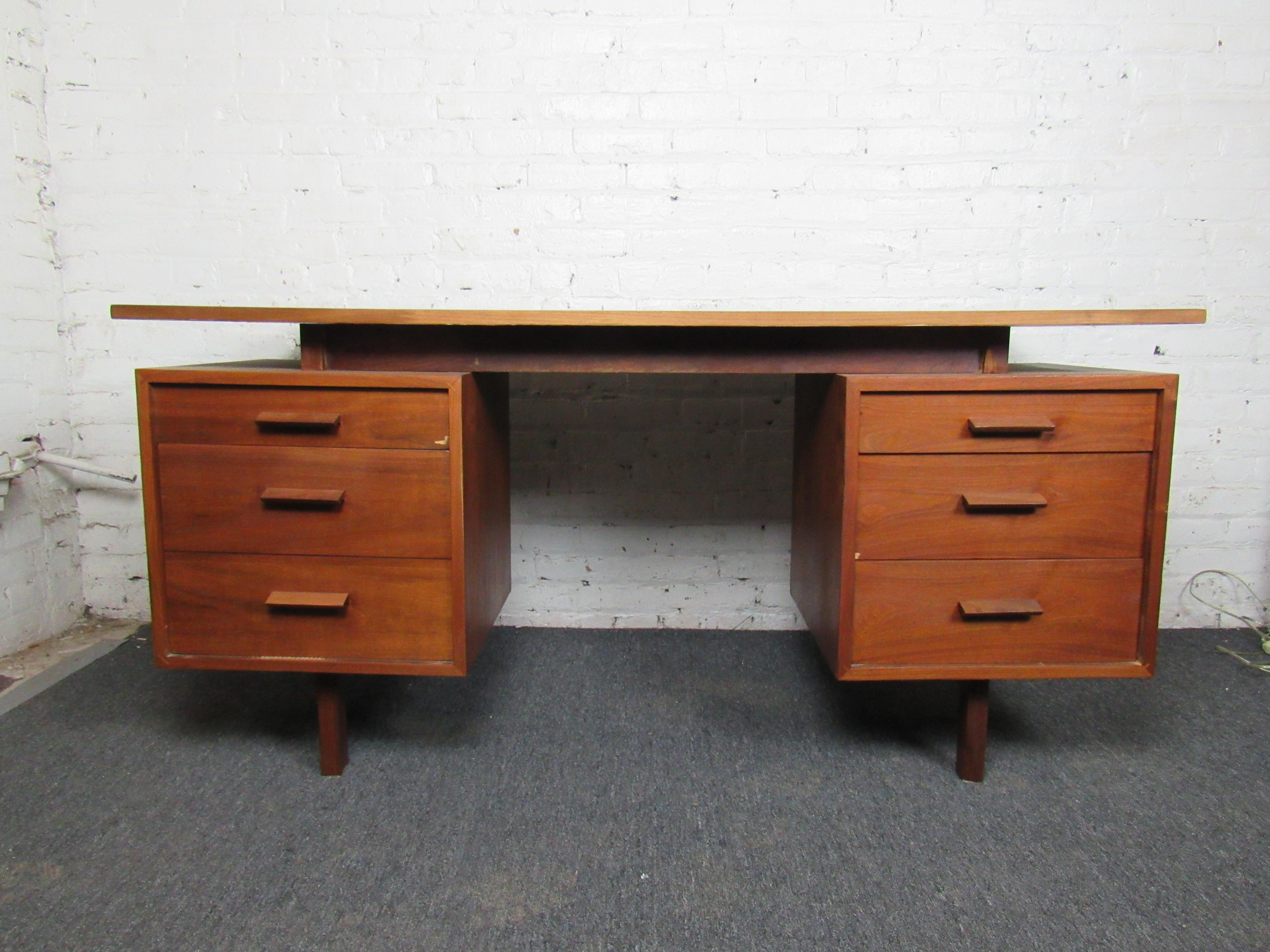 An incredible vintage desk full of Mid-Century Modern style and craftsmanship. Teak grain shows off a beautiful warm woodgrain and offers sturdy quality, while six drawers allow for storage and organization. Please confirm item location with seller