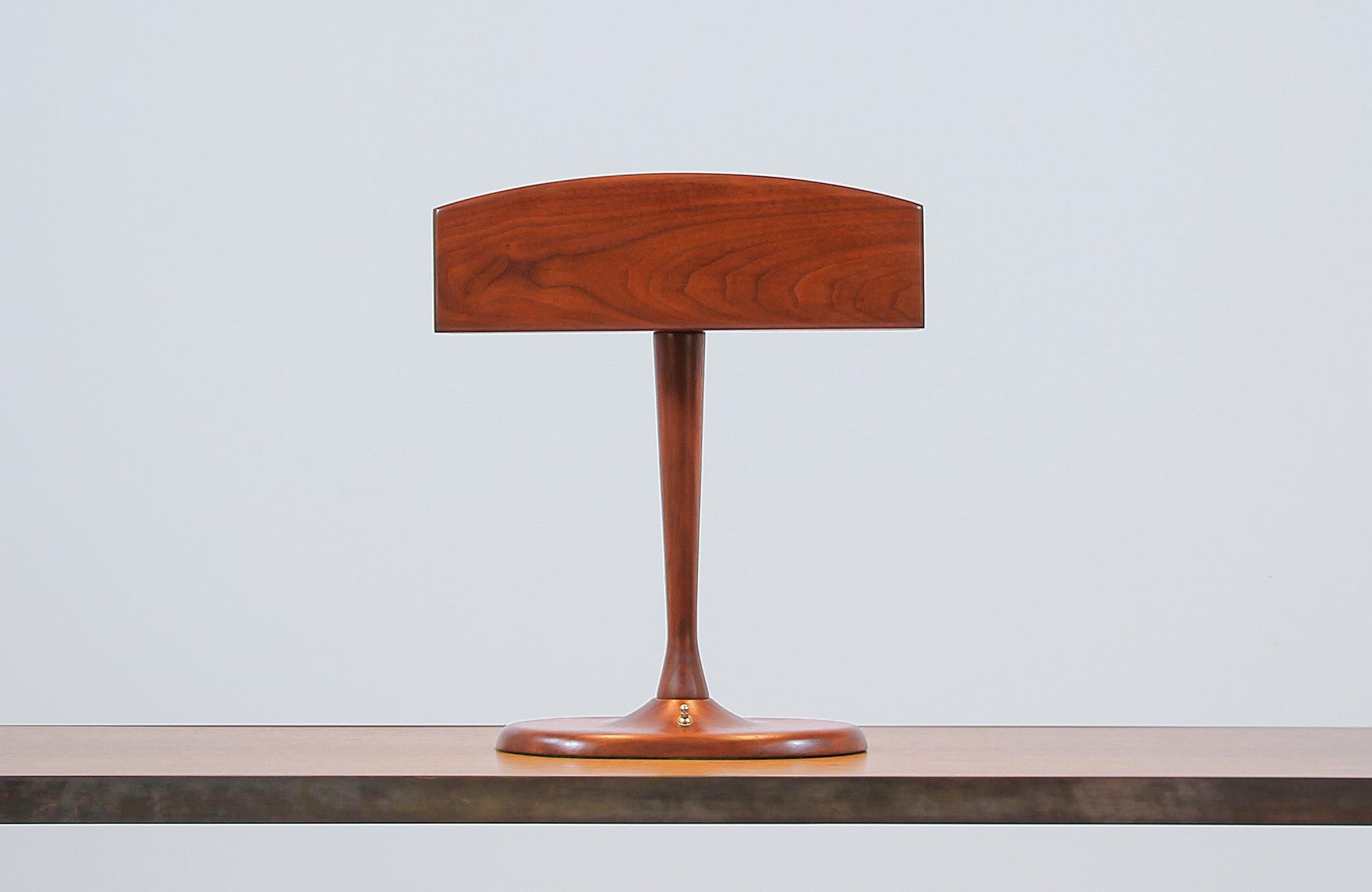 Beautiful modern desk lamp designed and manufactured in the United States circa 1960s. The mix of organic lines and midcentury aesthetic on this unique table lamp create a smooth, tall look on the warm walnut wood body finishes featuring a