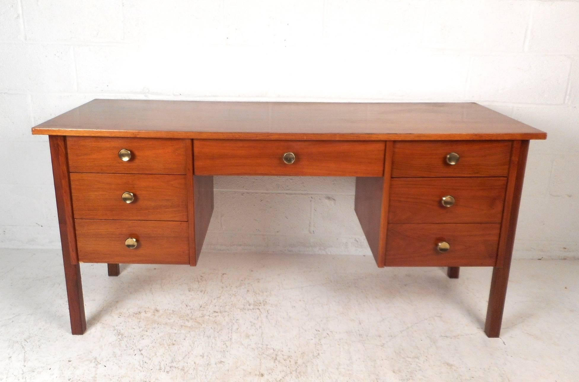 This gorgeous vintage modern desk features unusual circular metal pulls and an elegant walnut finish throughout. This impressive case piece offers plenty of room for storage within its seven drawers and ample work space on its 59.5 inch wide top.
