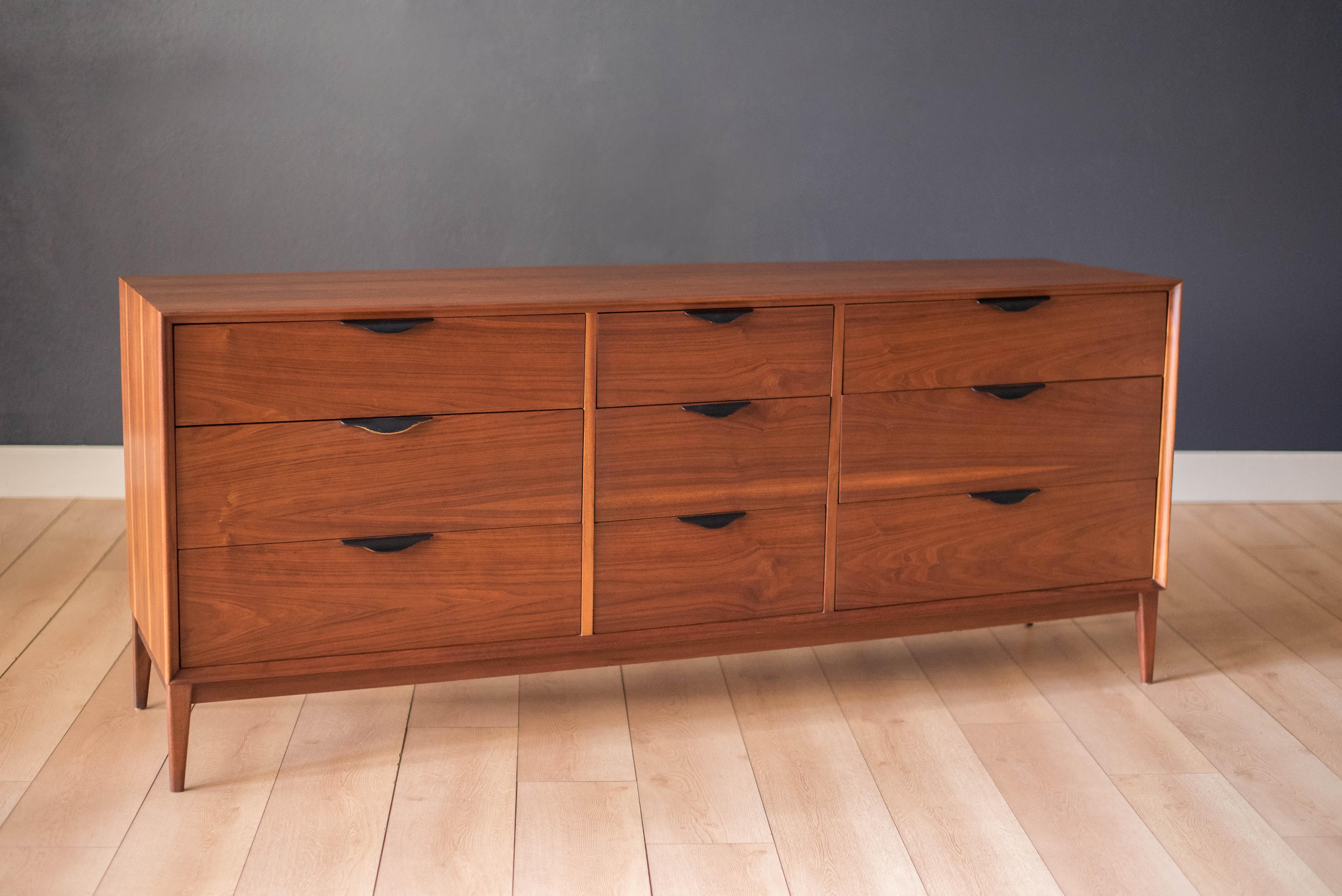 Midcentury dresser in walnut manufactured by Dillingham, circa 1960s. This piece includes nine spacious drawers of various sizes accessorized with sculpted ebonized wood pulls.