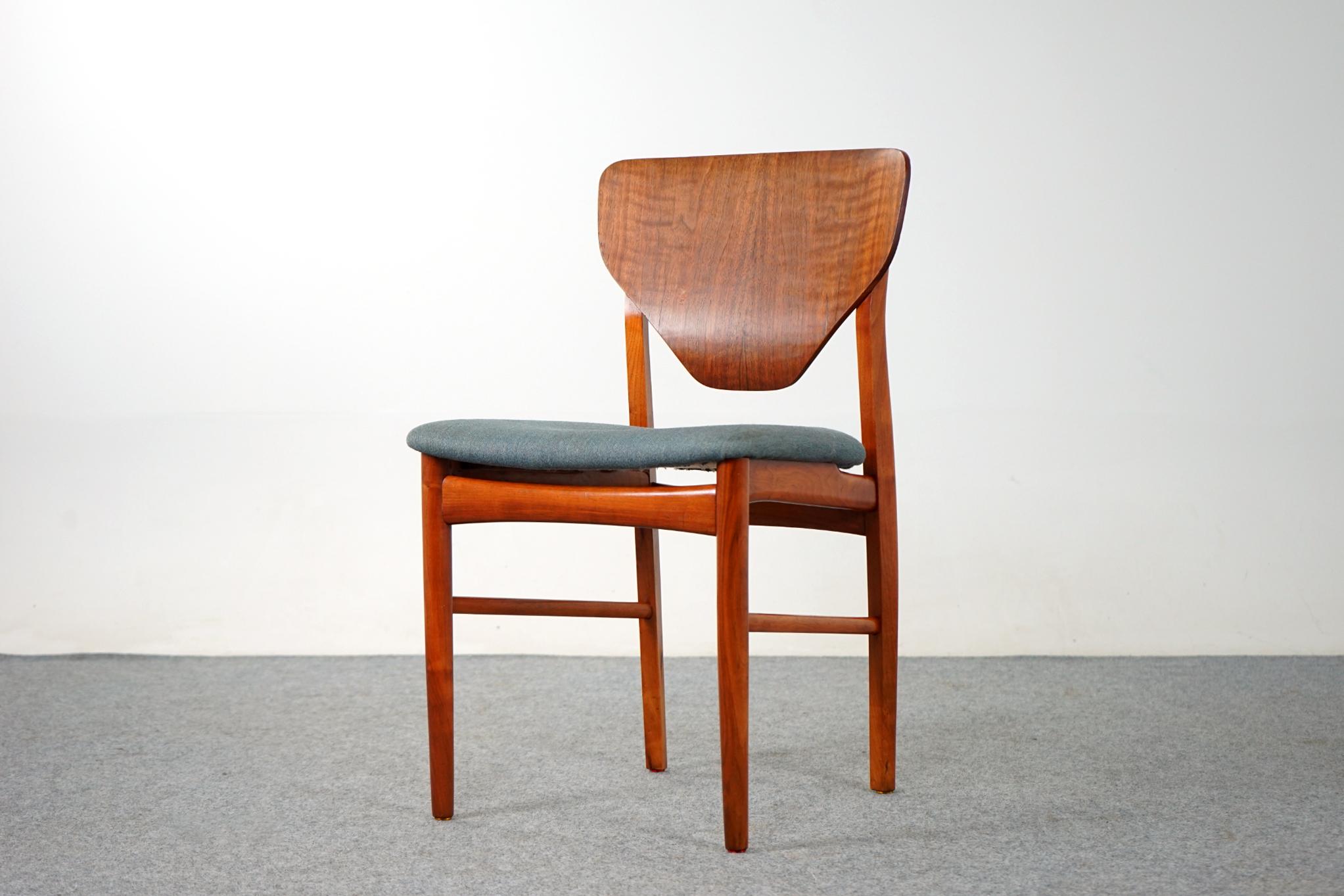 Walnut Danish dining chair, circa 1960's. Unique shield back design with integrated hidden hand pull on the back rest. Generous seat provided support and comfort, with some minor wear on the fabric. Solid wood legs feature bowtie cross braces for