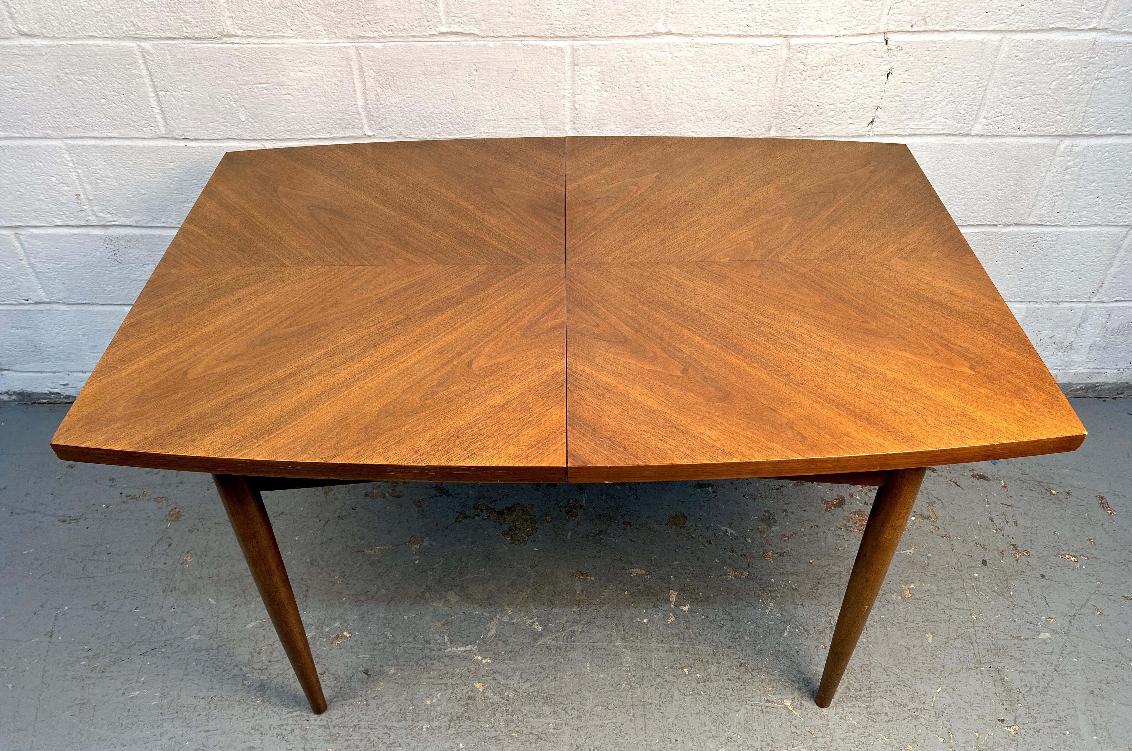 Magnifique table de salle à manger du milieu du siècle, fabriquée en noyer richement grainé et assorti. La pièce présente un design élégant et structuré et comprend deux feuilles d'extension pour plus de polyvalence. Un exemple raffiné d'artisanat