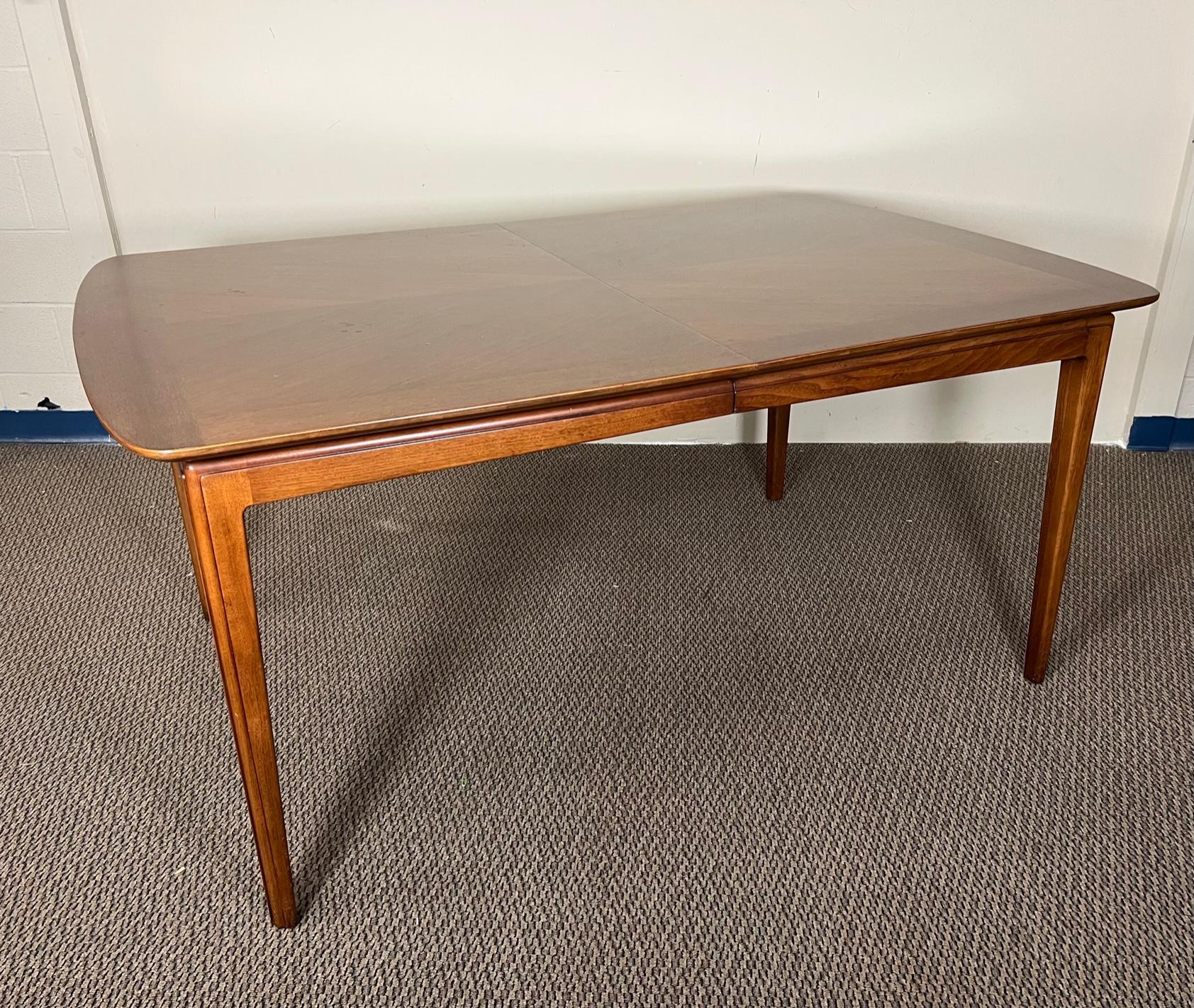 This is a large rectangular walnut dining table with rounded edges. It comes 2 extension leaves. Made by Henredon of North Carolina. Model circa'60. Original stamp underneath the table leaves. Fantastic condition. Minor marks. Small gouges.
