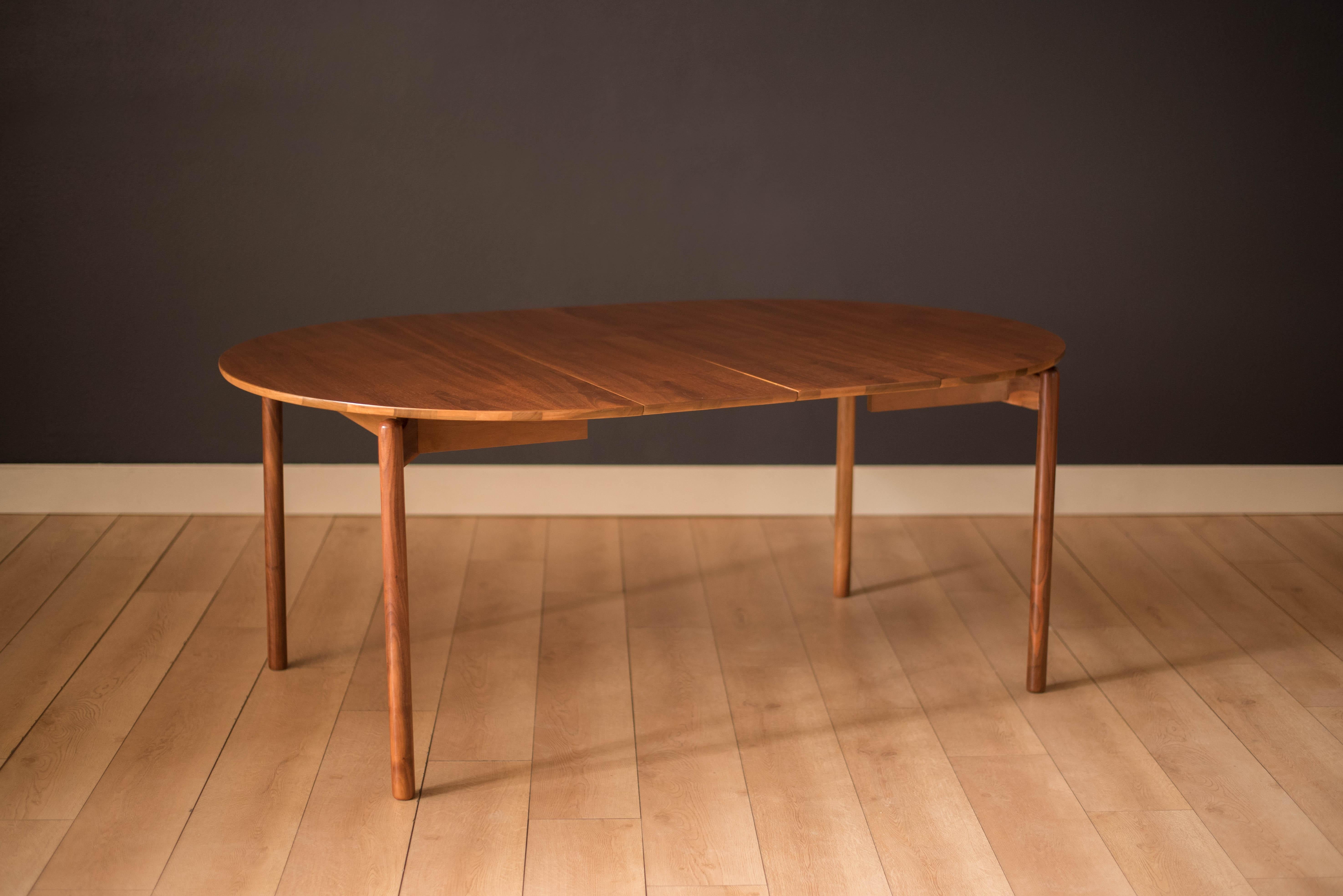 Vintage extendable dining table designed by Greta Magnusson-Grossman for Glenn of California. Features a walnut round table top suspended by a sculpted floating base design. This piece extends by using one or two leaves allowing more space for