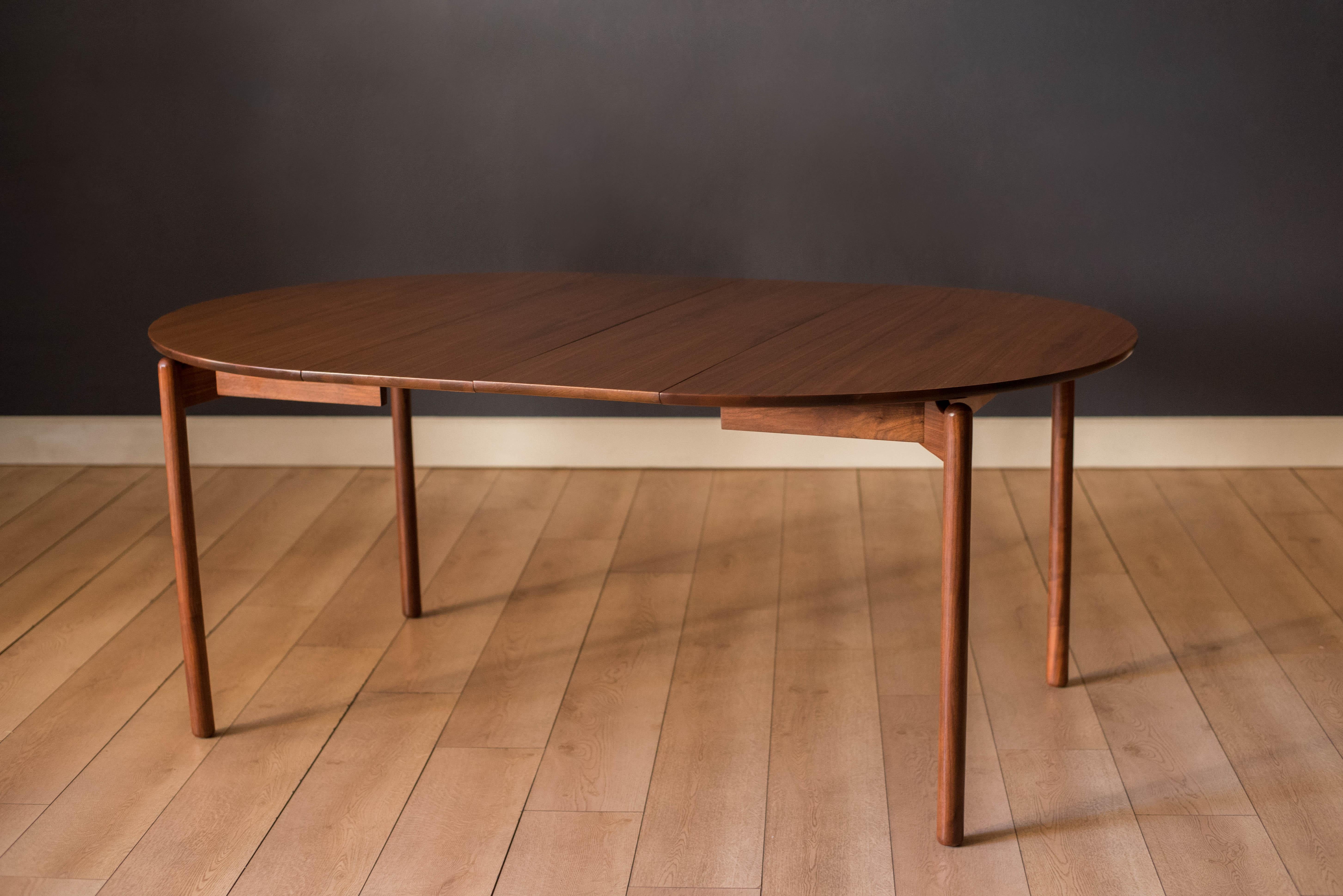 Vintage extendable dining table designed by Greta Magnusson-Grossman for Glenn of California. Features a walnut round table top suspended by a sculpted floating base design. This piece extends by using one or two leaves allowing more space for