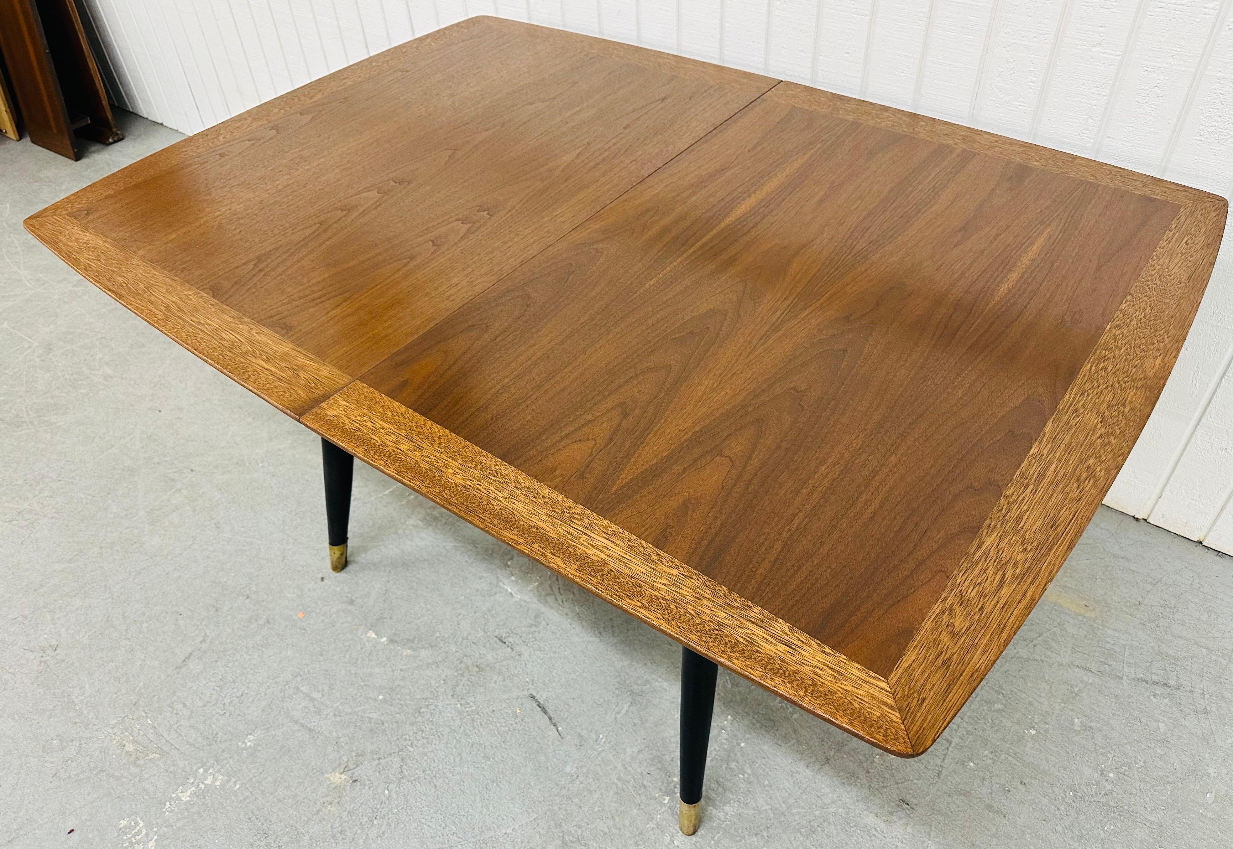 This listing is for a Mid-Century Modern Walnut Dining Table. Featuring a rectangular banded walnut top, ebonized legs with brass caps, and one leaf that extends the table to 72” L. This is an exceptional combination of quality and design!