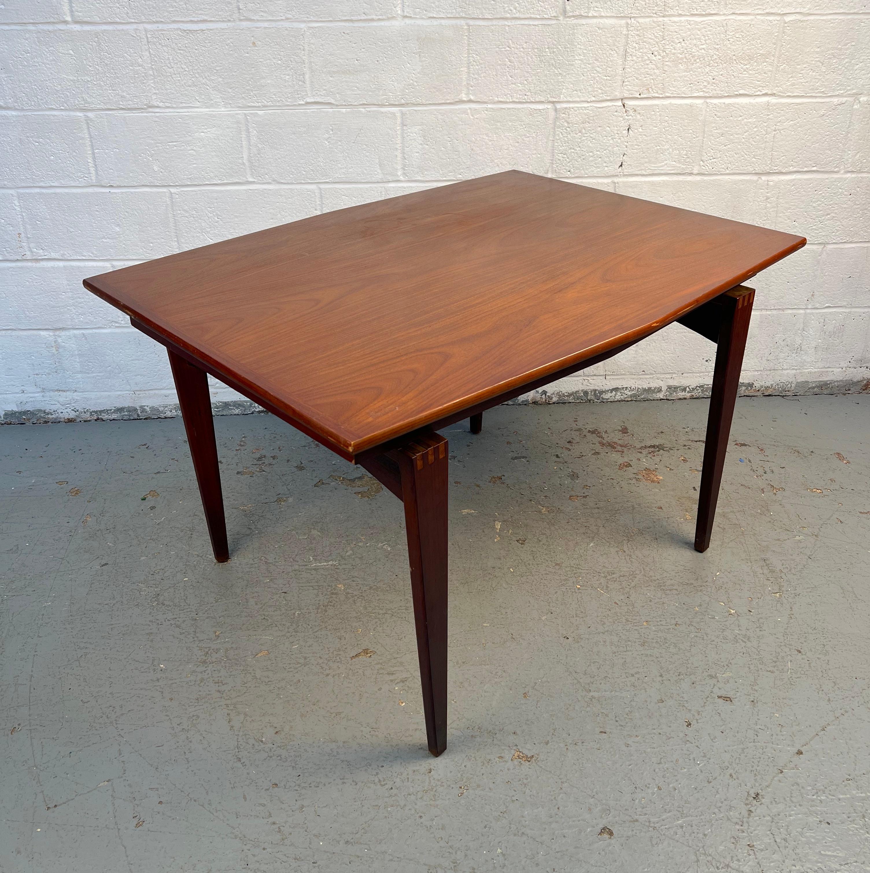 Perfetto connubio tra artigianato e design classico, questo tavolo da pranzo Mid-Century Modern è ideale per spazi intimi senza rinunciare allo stile. Realizzato in noce, presenta una finitura calda che mette in risalto le ricche venature e il