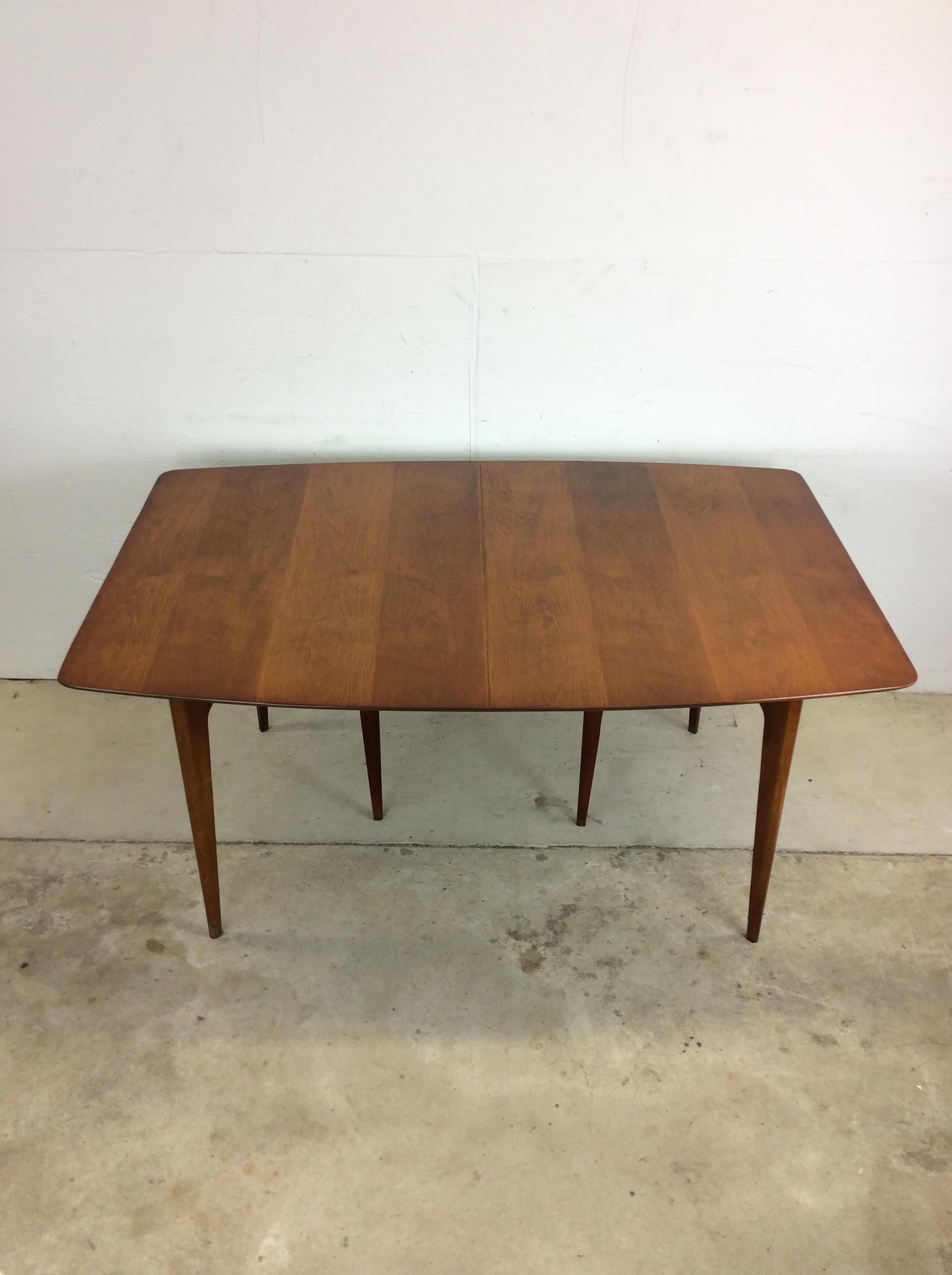 Esta mesa de comedor moderna de mediados de siglo está fabricada en madera dura, chapada en nogal con acabado original, patas altas cónicas en configuración triangular y una hoja extraíble. u2028u2028La hoja mide 12u2028u2028La longitud total con