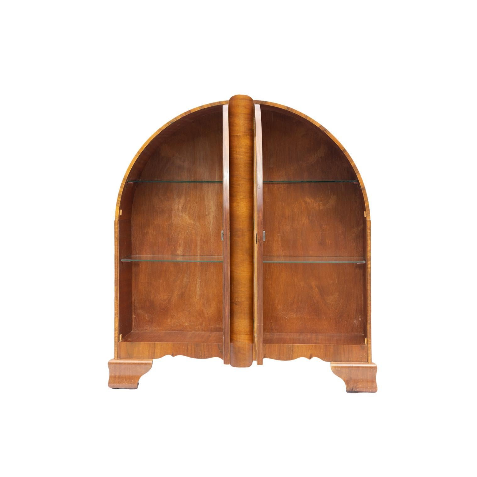 Mid-Century Modern walnut display cabinet, of Gothic shape, with glazed butterfly cabinet doors, on ogee bracket feet. 
British standard badge on the back with the date 1960 and license number 2150.