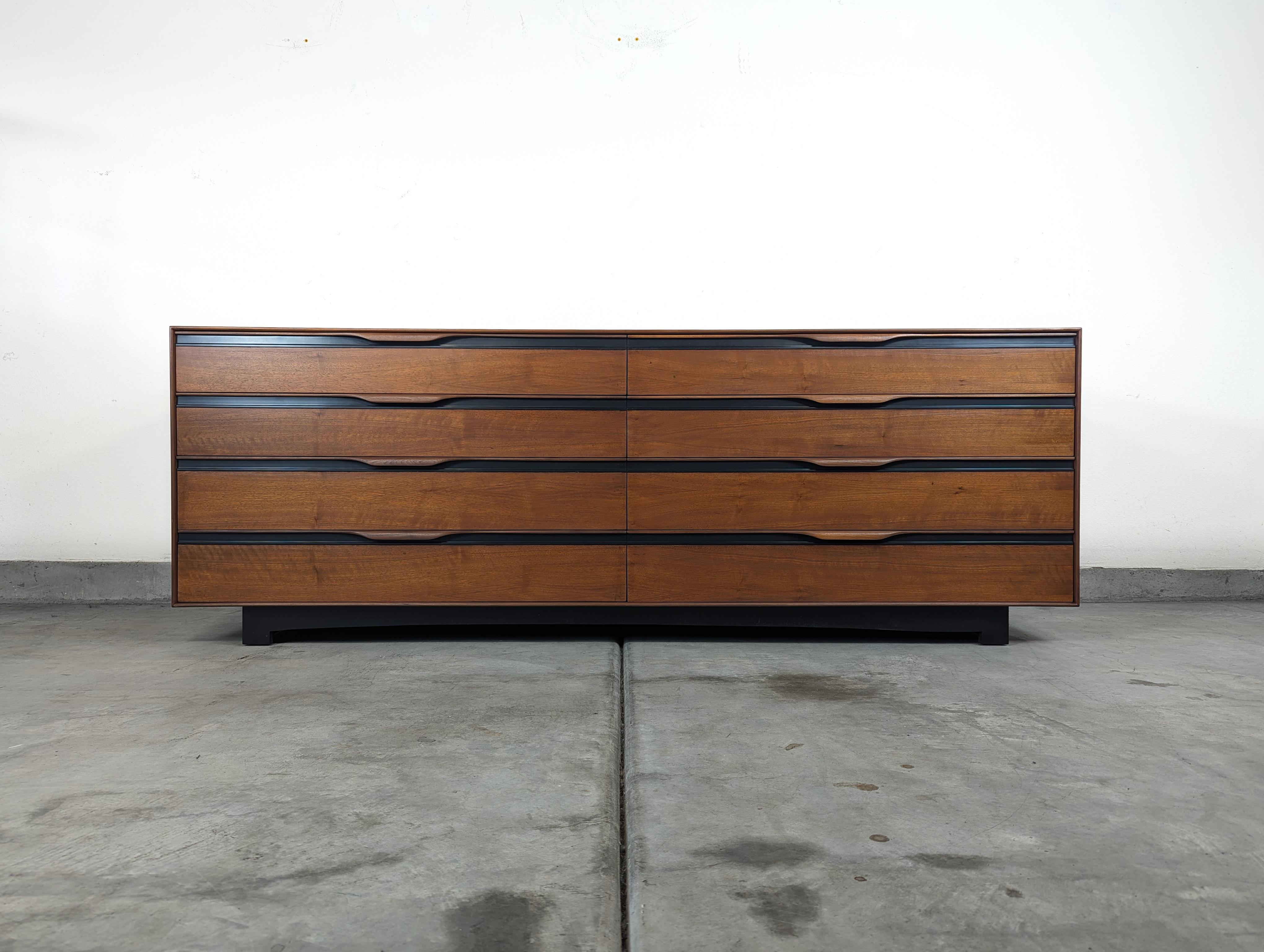 For sale is a stunning Mid Century Modern 8-Drawer Dresser designed by the renowned John Kapel for Glenn of California, circa 1960s. This exquisite piece boasts an amazing walnut wood grain that has been professionally refinished to perfection,