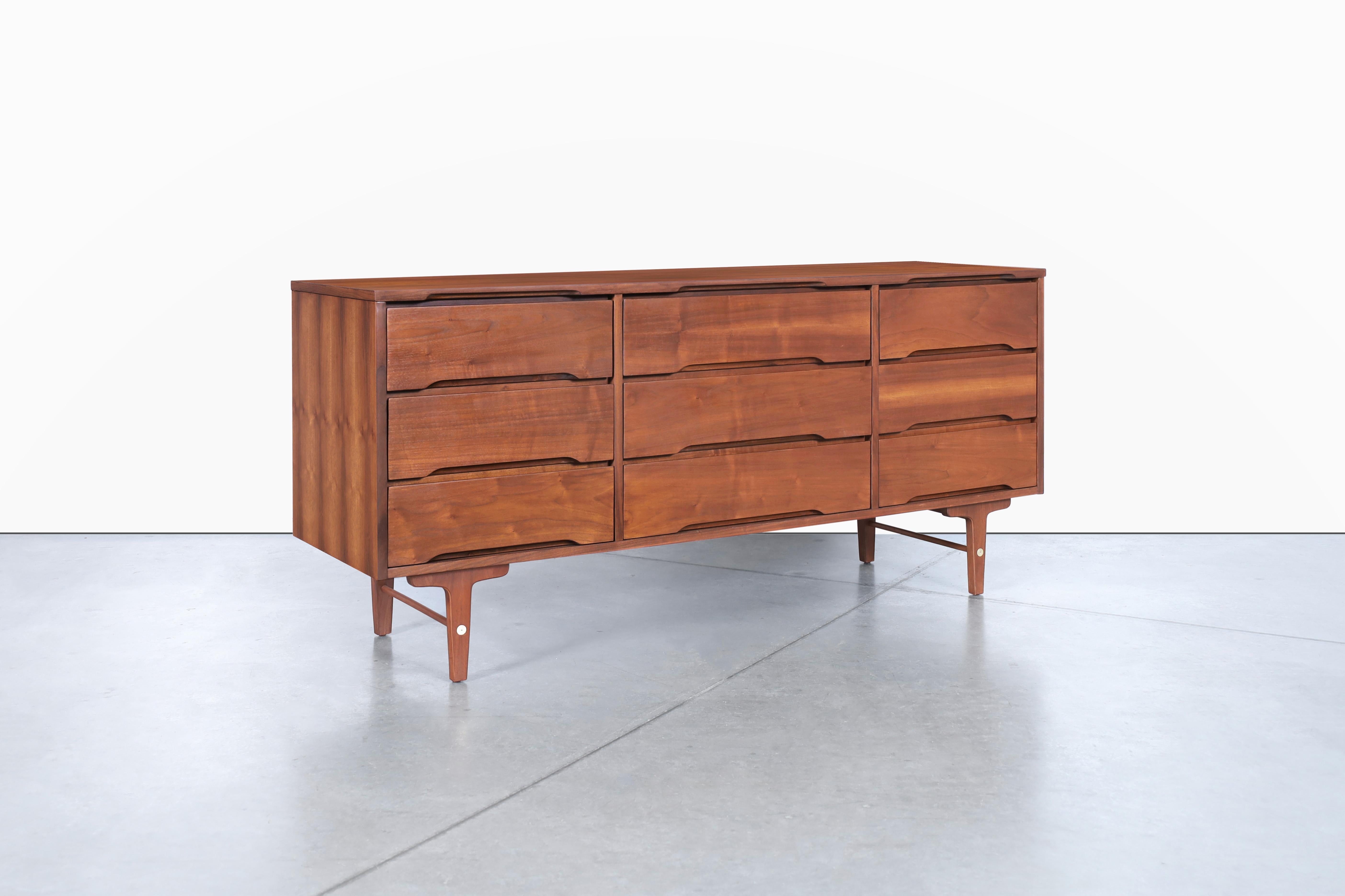 This stunning mid-century modern walnut dresser from Stanley Furniture is a true masterpiece of design and craftsmanship. Dating back to the 1950s, it boasts high-quality walnut construction and features nine dovetail drawers that offer ample