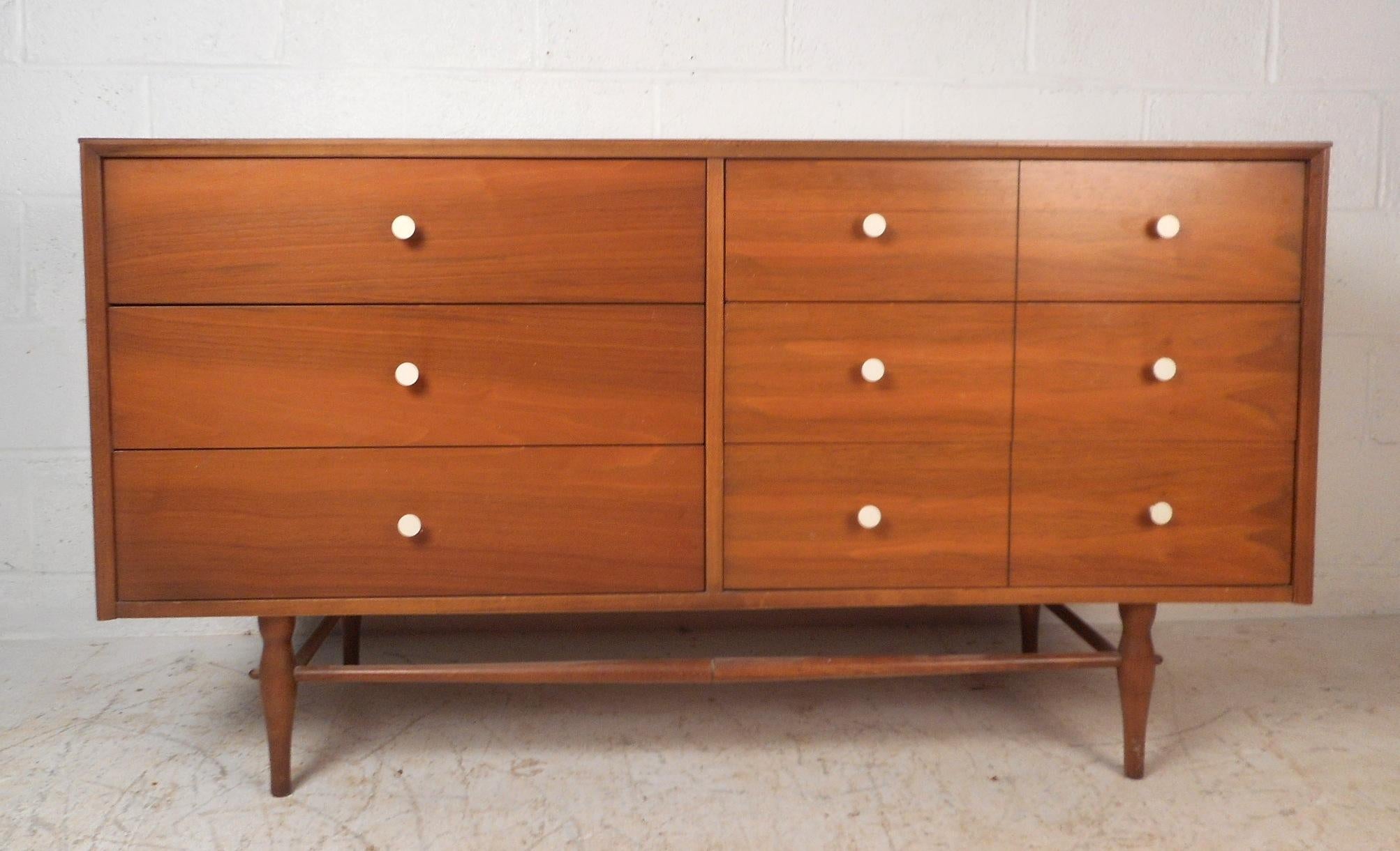This gorgeous vintage modern dresser features six hefty drawers ensuring plenty of room for storage. A petite straight line design with sculpted and tapered legs adding to the midcentury appeal. Unique circular white metal drawer pulls and an