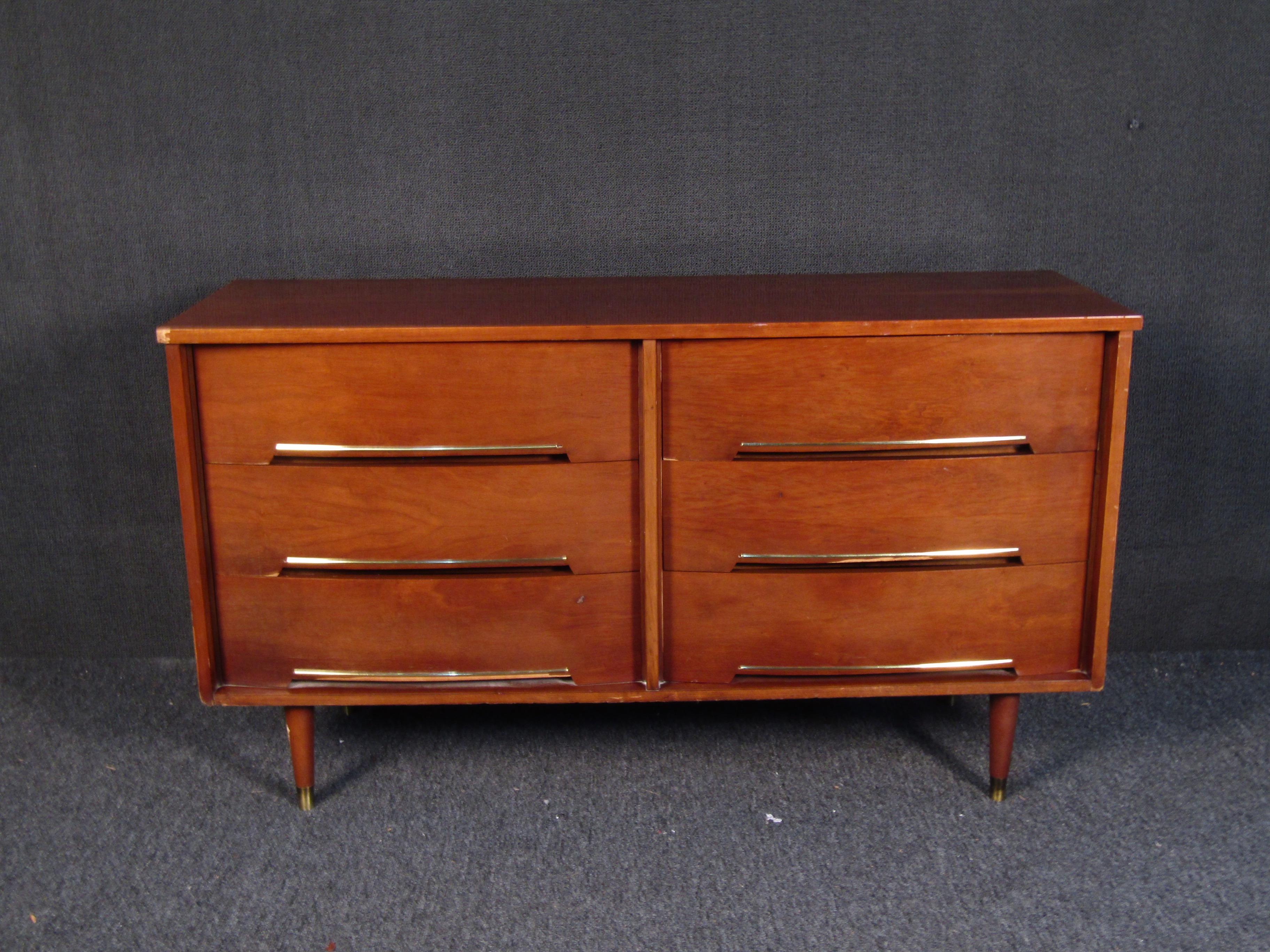 This vintage modern sturdy walnut dresser features brass inlays and inset drawer pulls. Its straightforward design and tapered brass-capped legs are sure to fit in any modern home. Confirm pickup location(ny/nj).