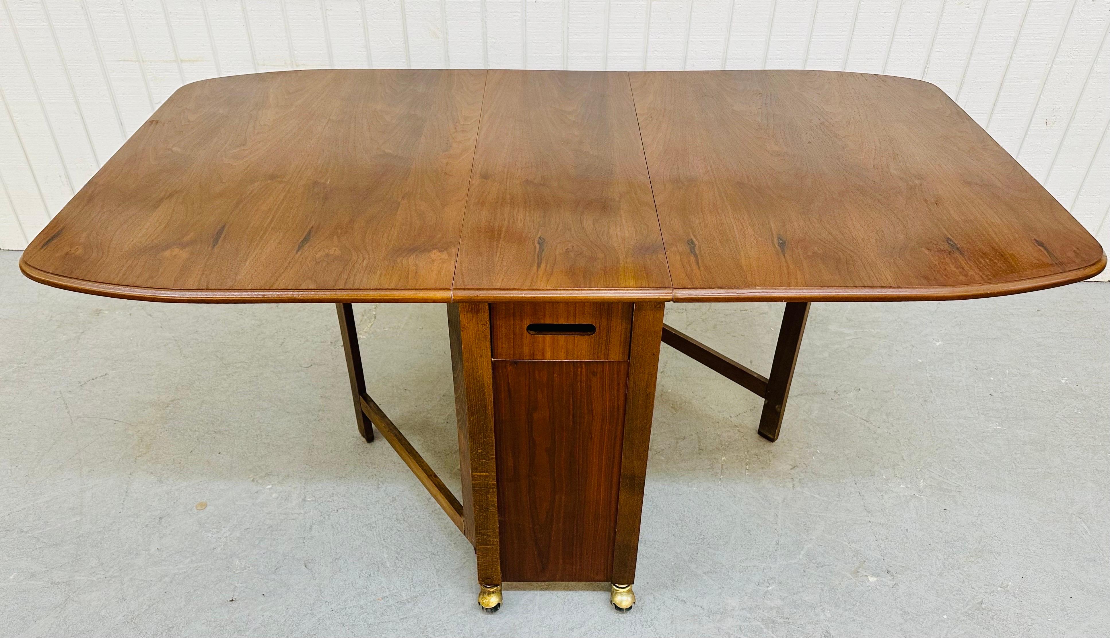 This listing is for a Mid-Century Modern Walnut Drop Leaf Dining Set. Featuring a walnut drop leaf table, four folding chairs with padded seats, original wheels, a pull out drawer for storage, and storage space for the four chairs. This is an