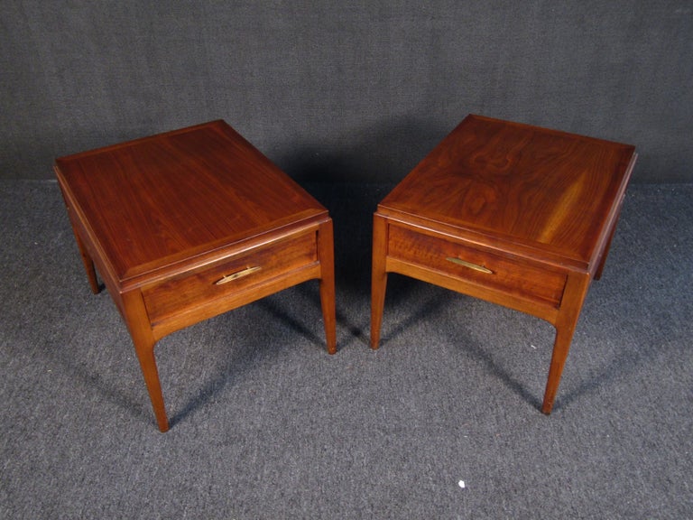 This stylish pair of vintage modern end tables features a rich walnut finish and sturdy construction. Striking yet simple mid-century end tables work well in a living room or waiting room, and add warm vintage wood tones to home or business decor.