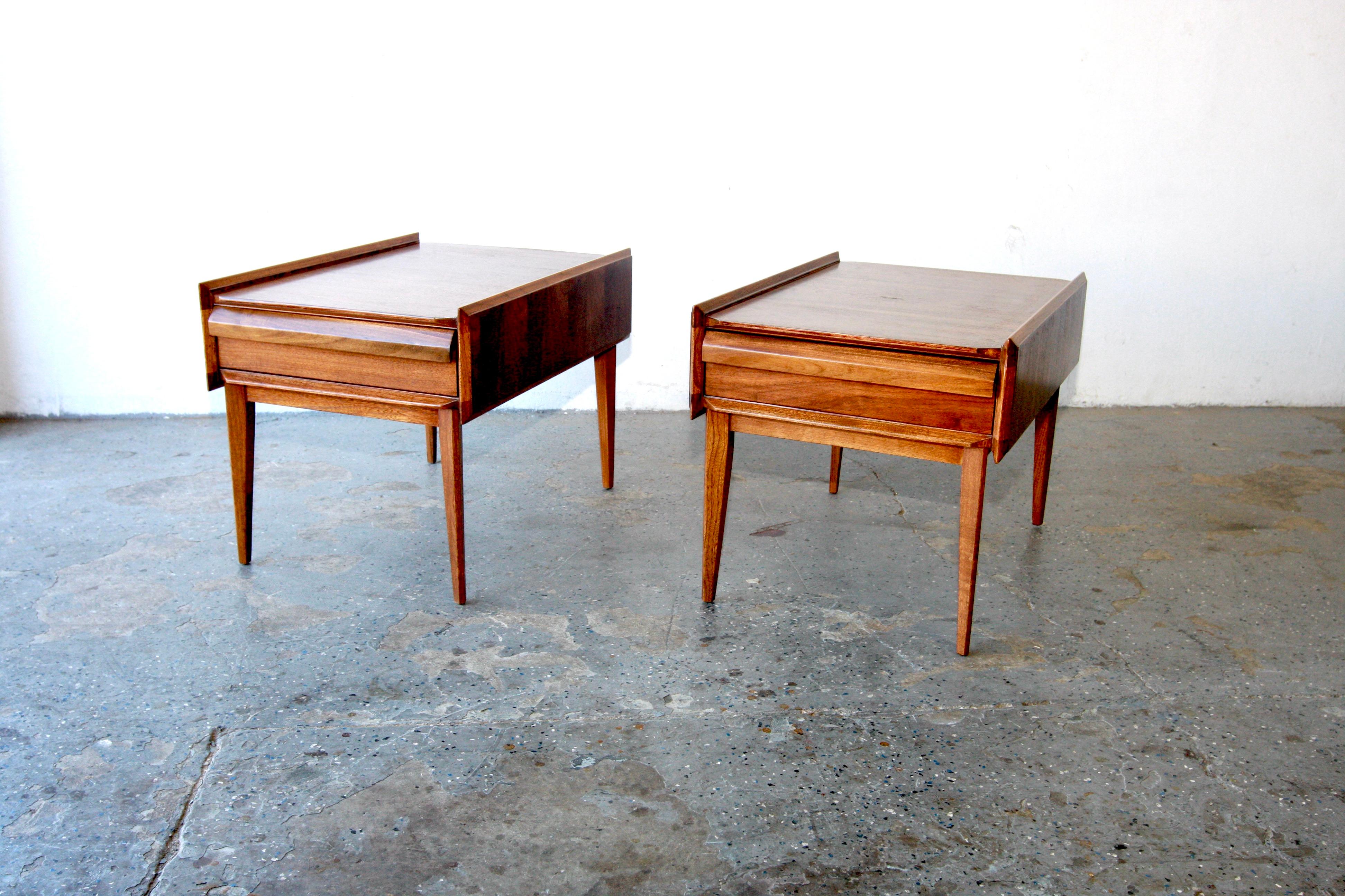 This eclectic pair of walnut end tables designed by Andre Bus for the First Edition Collection by Lane C. 1966 features sharp angles, built up sides and a sculpted drawer front.  Because of its Danish influence, this line is also known as the