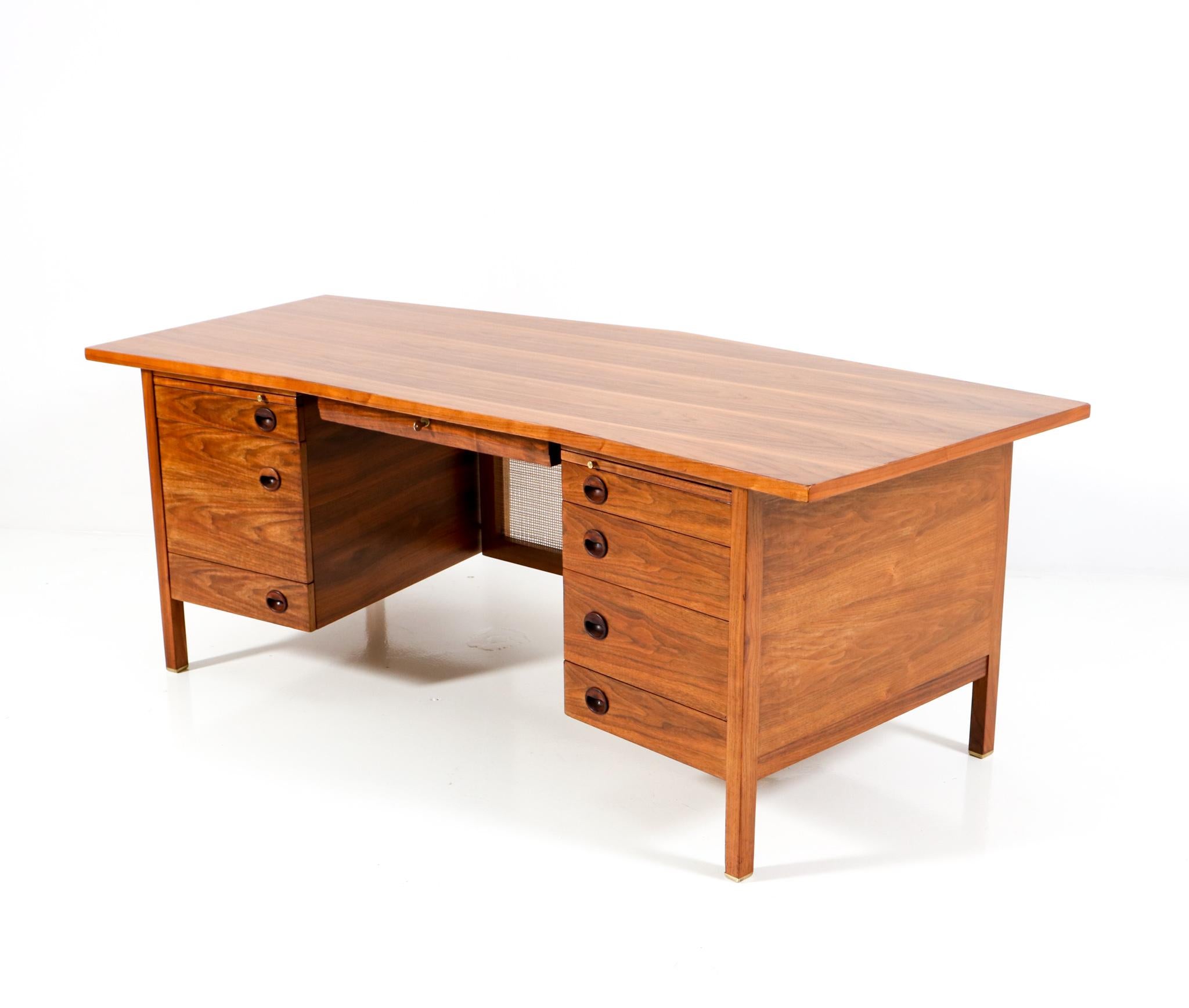 Magnificent and ultra rare Mid-Century Modern executive desk. Design by Edward Wormley for Dunbar Furniture United States. Striking American design from the 1950s. Solid walnut base on brass feet. Original walnut veneered top. Eight original drawers