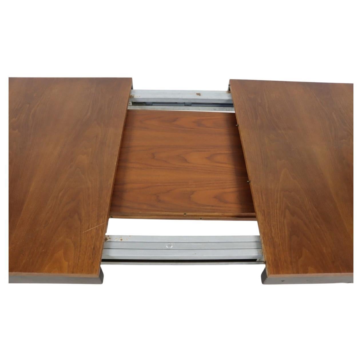 Mid century modern original walnut extension dining table designed by George Nelson for Herman Miller with 2 leaves. This dining table has a walnut top with 2x walnut leaves that stow away in the table. The legs and base of the table is made of