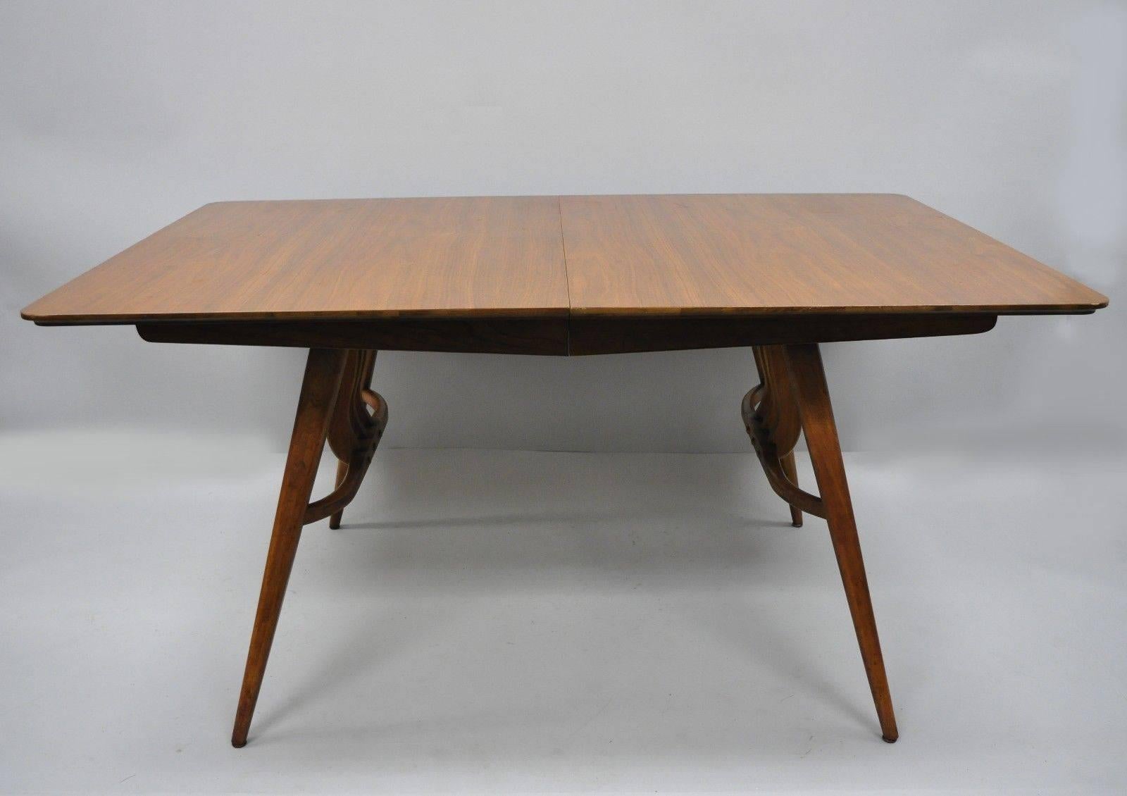 Vintage Mid-Century Modern walnut extension dining table with three-leaves and sleek harp / lyre form base. Maker unconfirmed but very similar to the works of American of Martinsville. Item features three 12