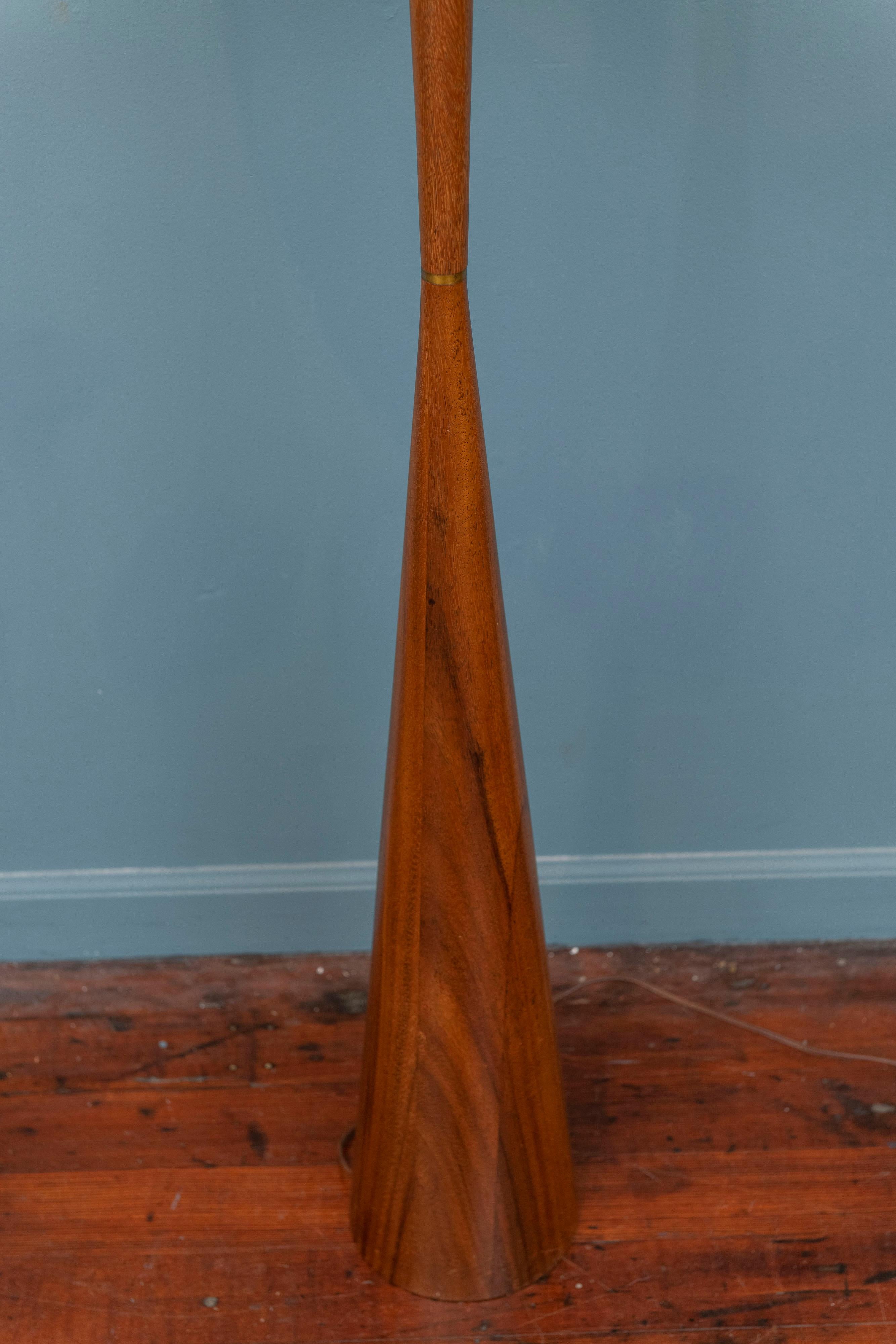 Mid-Century Modern turned walnut floor lamp in the style of Phillip Llyod Powell. Sophisticated simple design of inverted triangles tapering towards a brass collar in the center. Newly refinished, original wiring in working order.