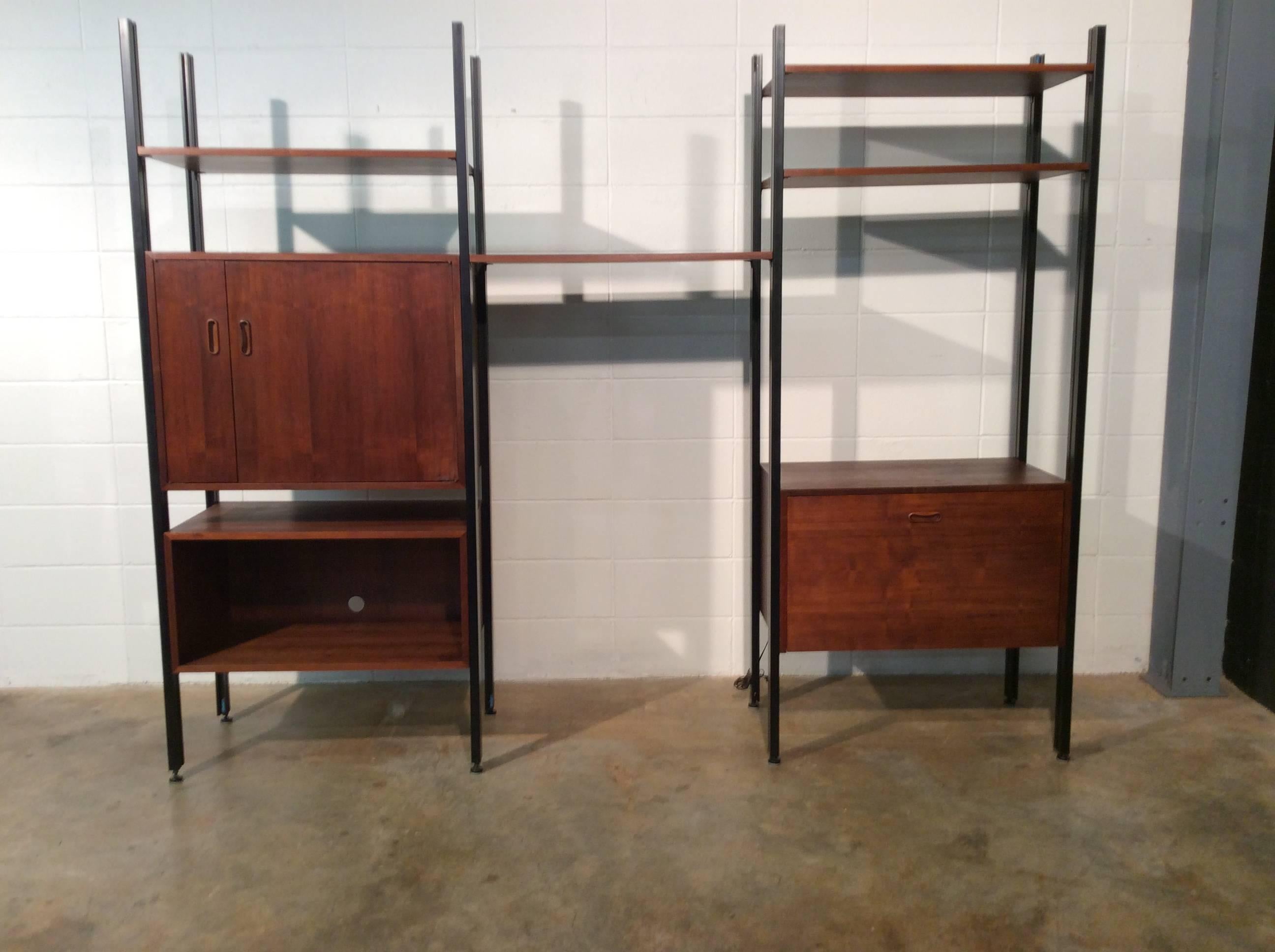 Mid-Century Modern walnut freestanding three bay Omni unit by George Nelson.
This freestanding unit includes eight poles, three different cabinets, four shelves, and mounting hardware for all of it.
All pieces are in good original condition. All