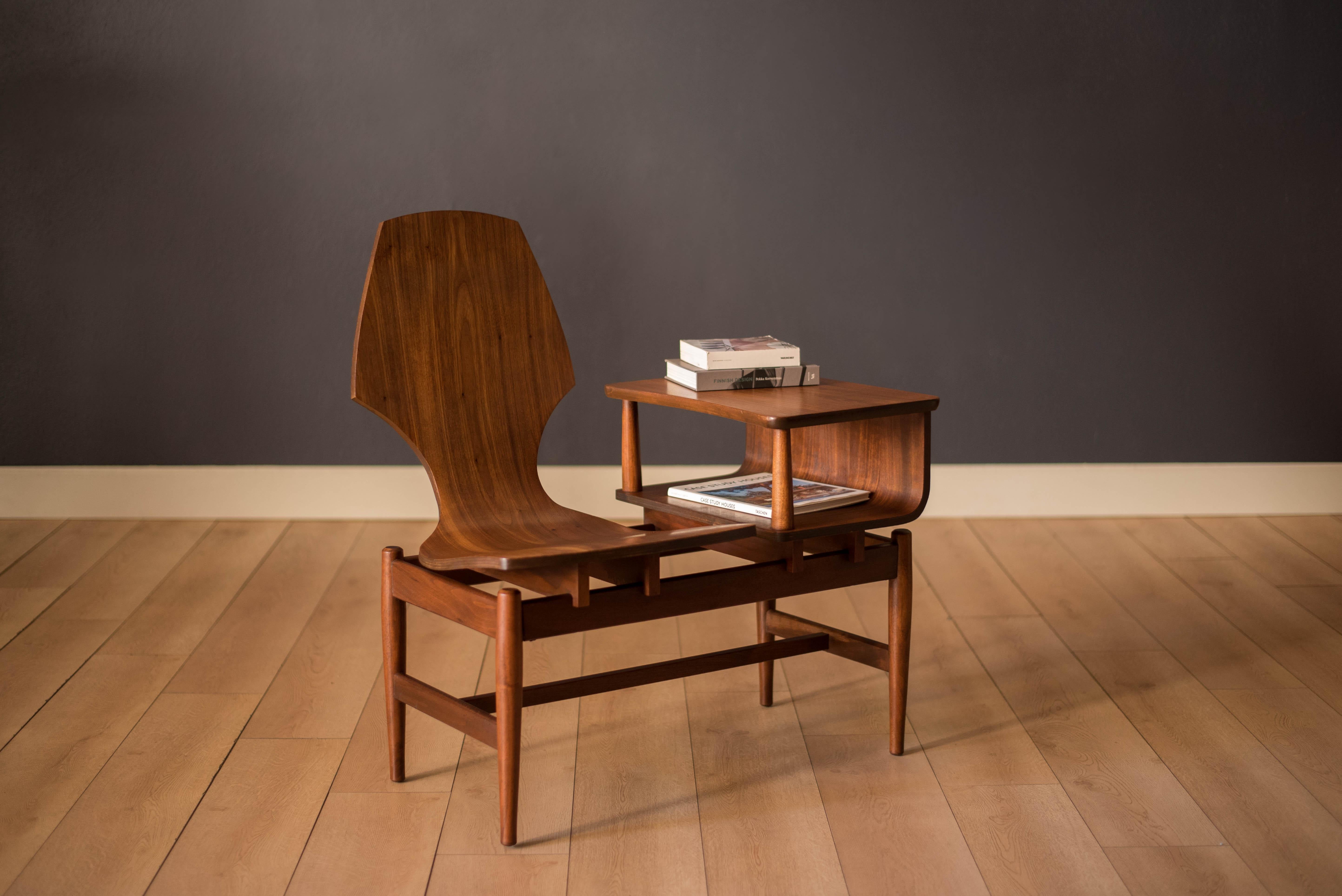 Mid-Century Modern gossip bench with telephone table manufactured by Plycraft circa 1960's. This unique piece features stunning walnut grains that includes one floating seat and a bent laminated plywood end table. Perfect to use in the entryway or