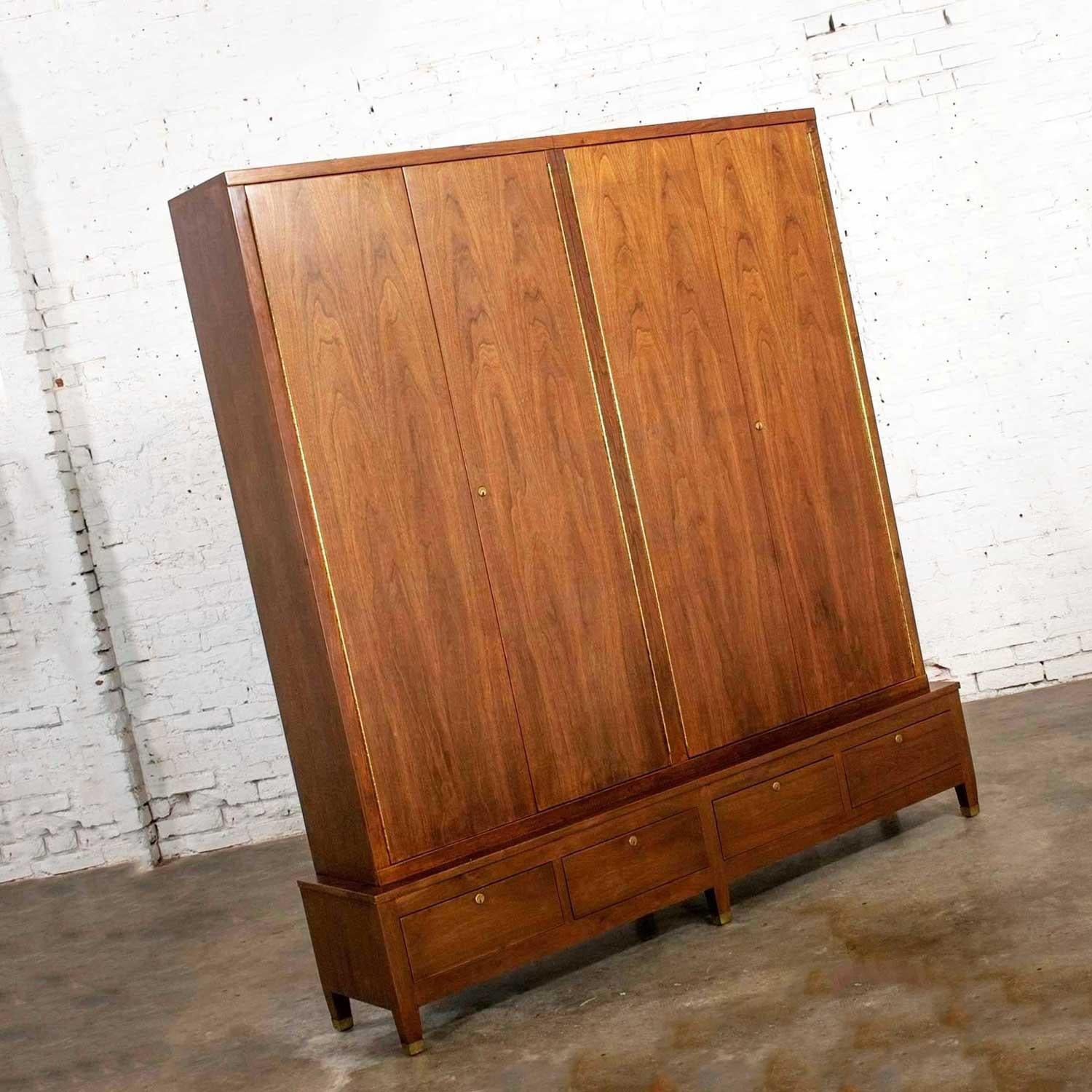 Handsome Mid-Century Modern gun cabinet comprised of walnut with brass sabots and locking mechanism. Gorgeous vintage condition, one of the lower skirts on the base has some rippling due to moisture sometime in its life but it does not distract from