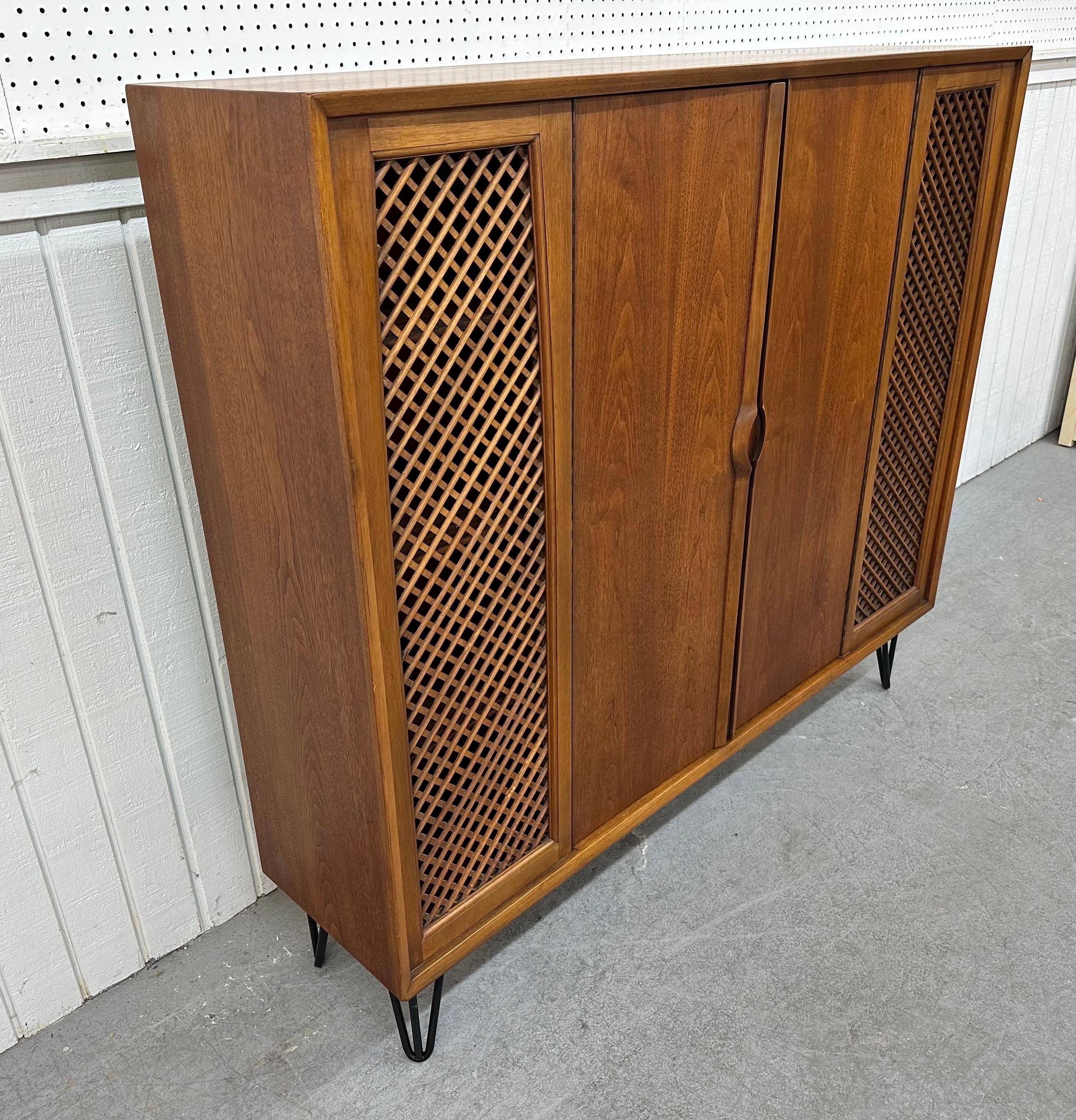 This listing is for a Mid-Century Modern Walnut Hairpin Bookcase. Featuring a straight line design, two doors that open up to storage space, wooden pulls, hairpins legs, and a beautiful walnut finish. This is an exceptional combination of quality