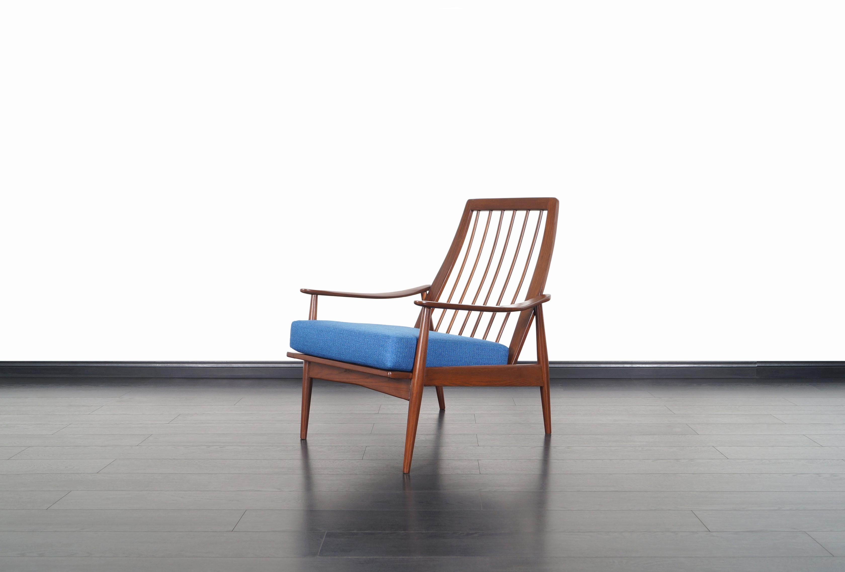 Fabuleux fauteuil de salon moderne du milieu du siècle, fabriqué aux États-Unis, vers les années 1950. Cette chaise présente une structure en chêne massif teinté noyer avec des accoudoirs sculpturaux et un dossier à lattes. Les proportions