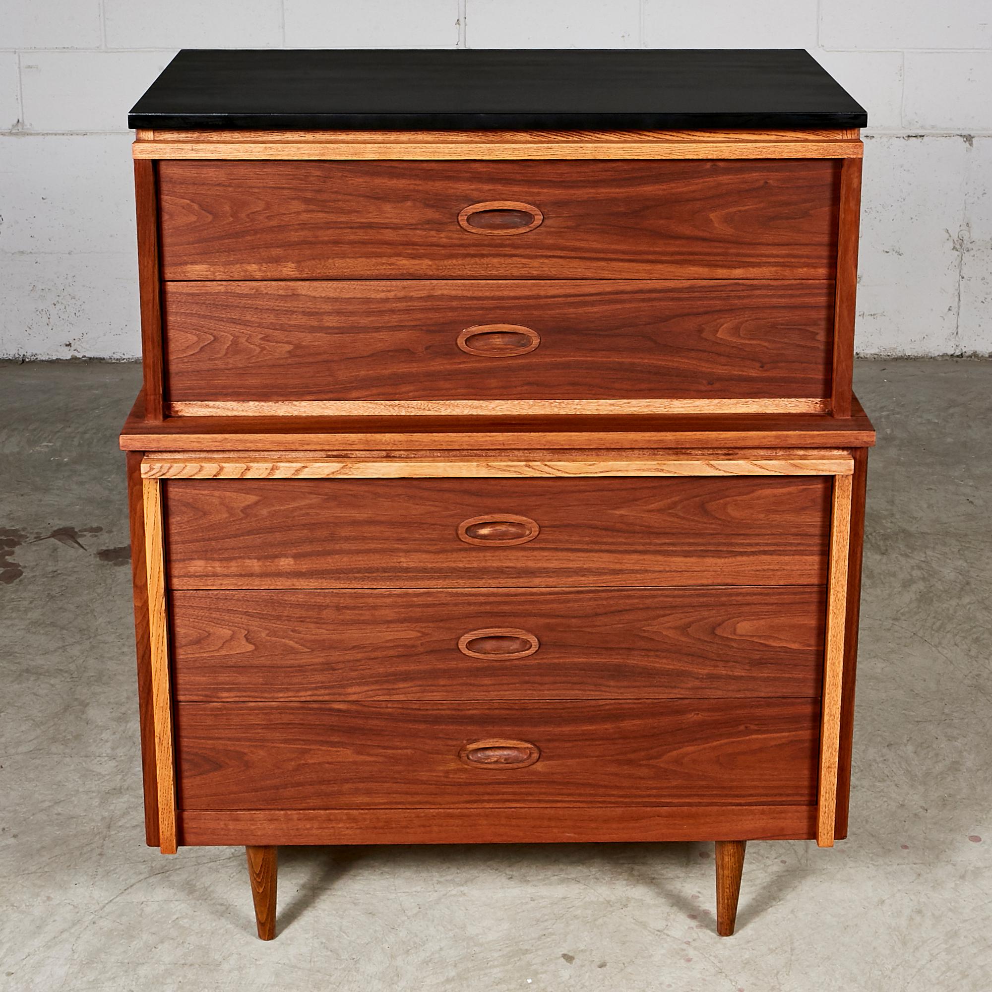 Mid-Century Modern 1960s walnut and ash wood high boy dresser with a black painted top manufactured by Dixie Furniture Co. The dresser has five drawers for storage and oval inset drawer pulls. In newly refinished condition. Marked.