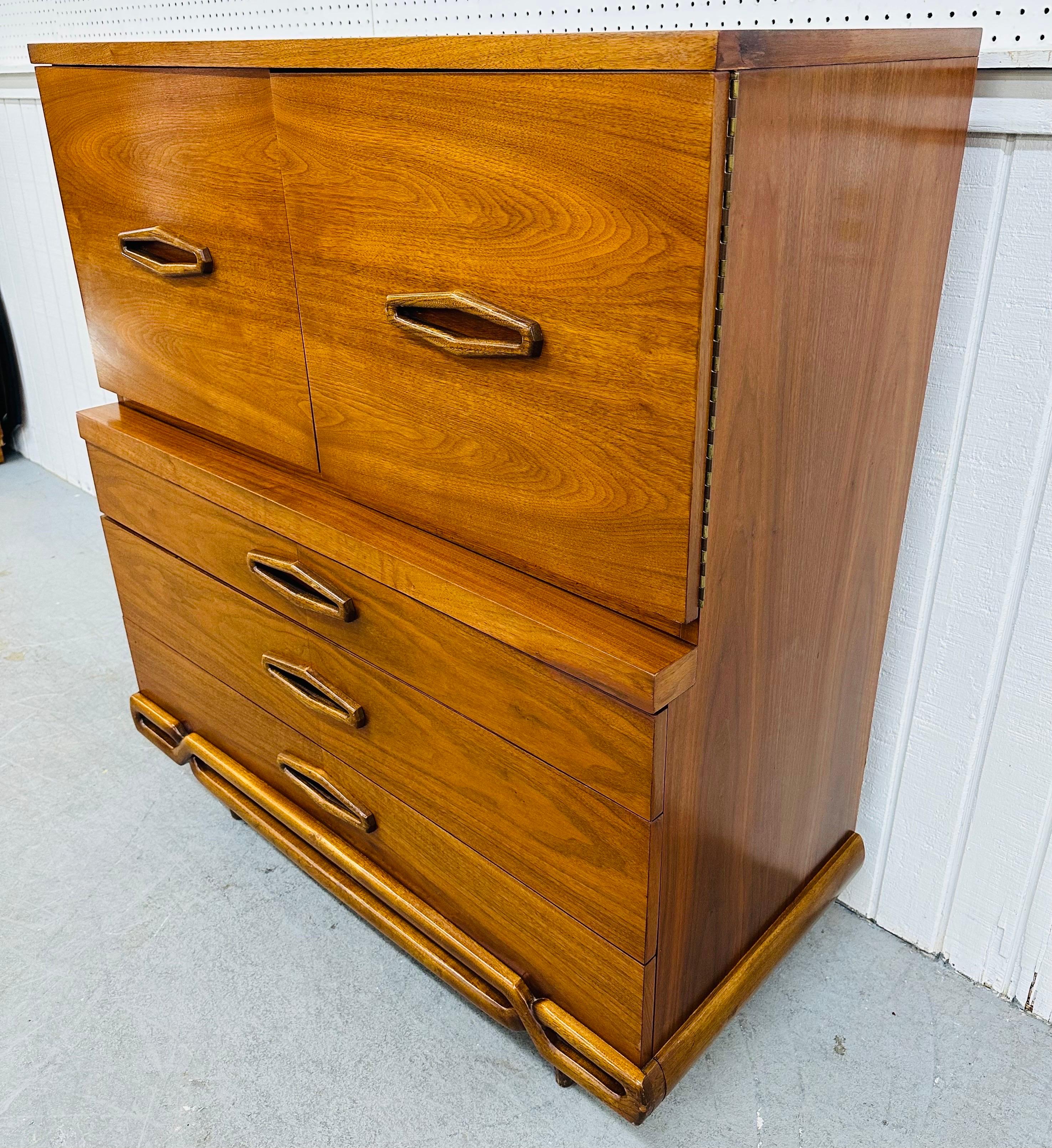 This listing is for a Mid-Century Modern Walnut High Chest. Featuring a straight line design, two doors with recessed wooden pulls, two large hidden drawers, three more larger drawers at the bottom, modern legs, and a beautiful walnut finish.