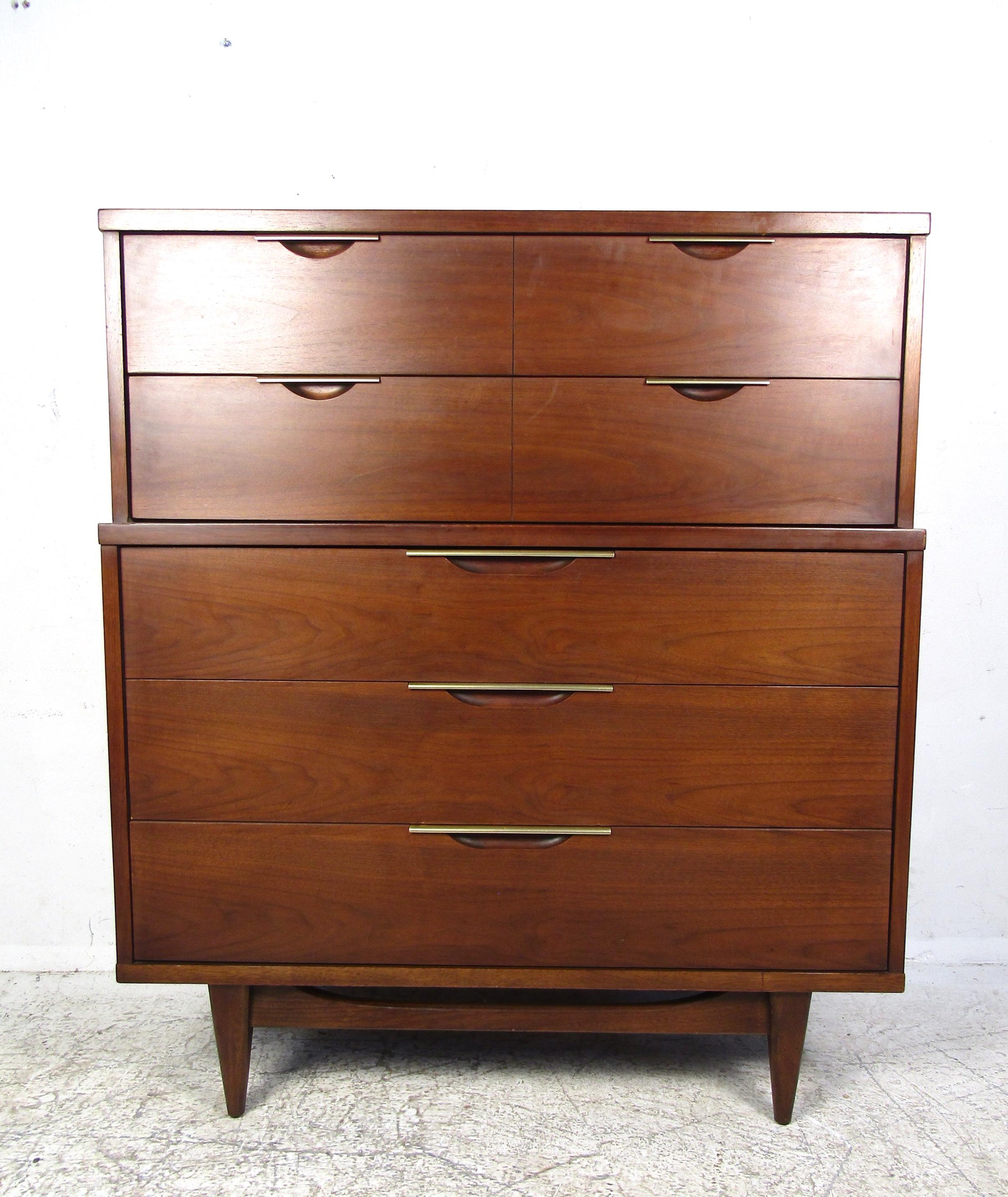 A stunning vintage modern highboy dresser by Kent Coffey. Plenty of room for storage within its five hefty drawers. The sculpted base, tapered legs, and unusual metal stripped drawer pulls make this case piece stand out from the rest. An elegant