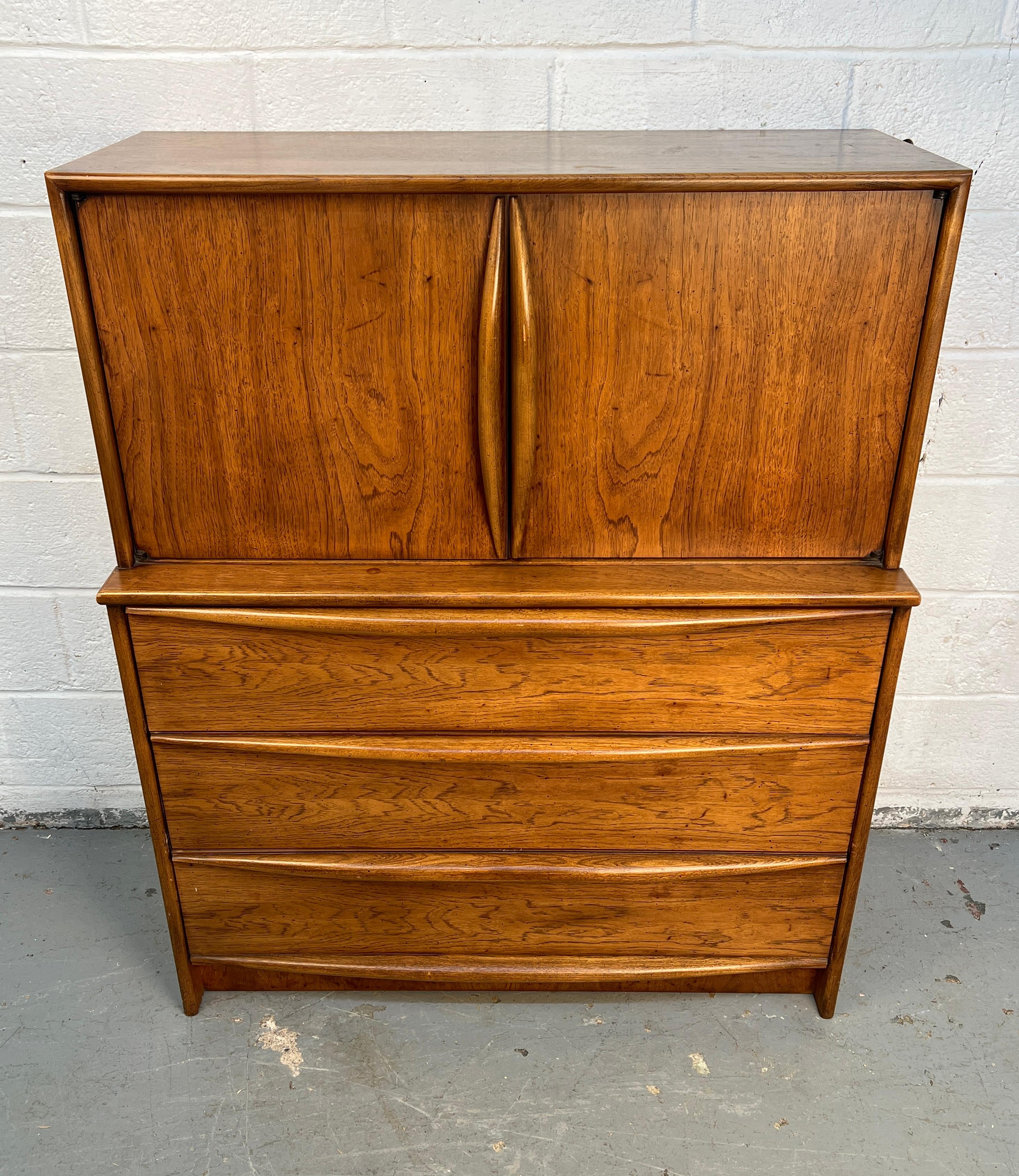 Cómoda clásica de mediados de siglo fabricada en nogal por Lane Furniture. Presenta líneas limpias, detalles escultóricos y amplios cajones de cola de milano, mostrando la excepcional artesanía y el diseño atemporal que definen las icónicas