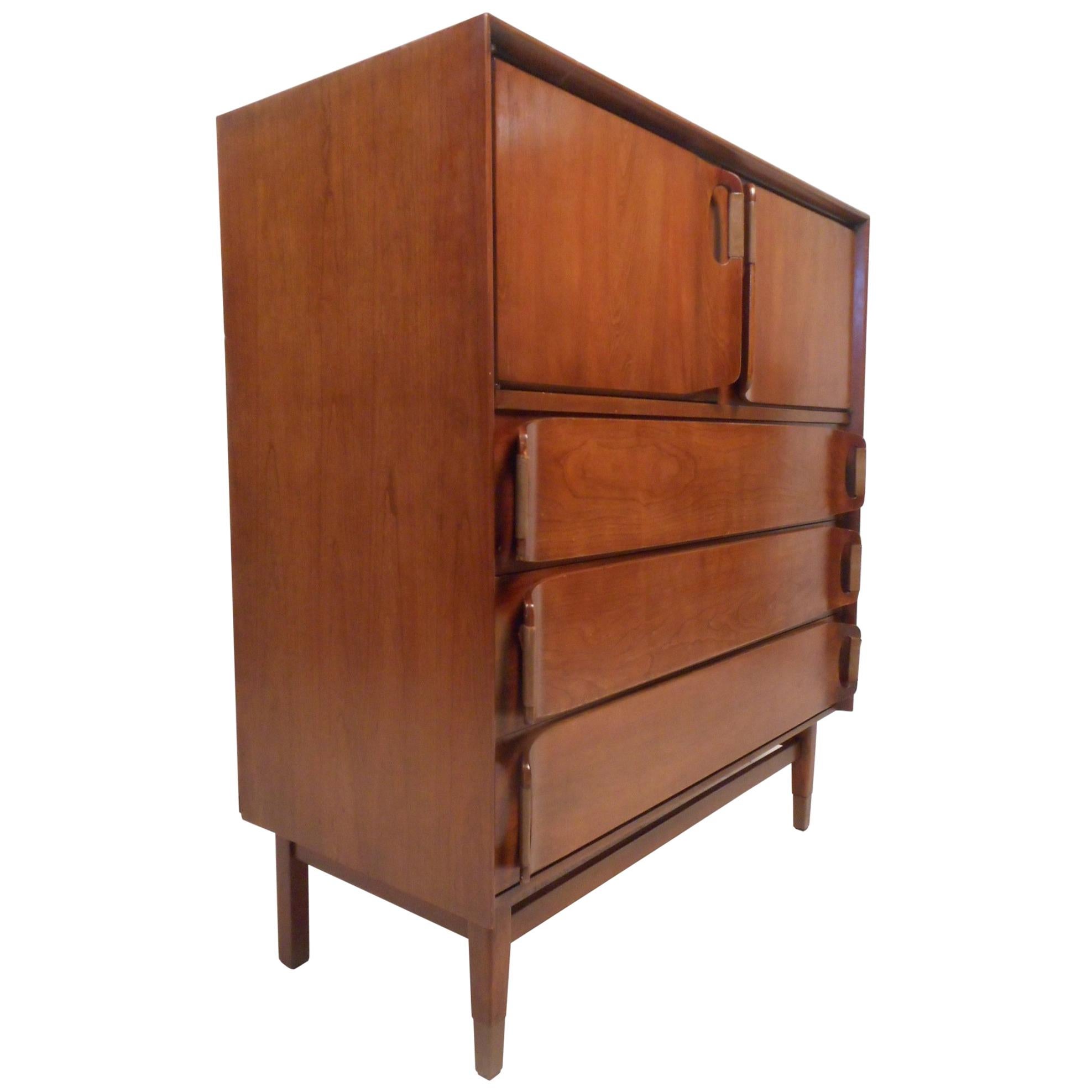 This unique vintage modern dresser features sculpted drawer pulls with leather and brass capped feet. A sleek design with ample storage space within its three hefty drawers and large compartment hidden by two cabinet doors. Sturdy construction with