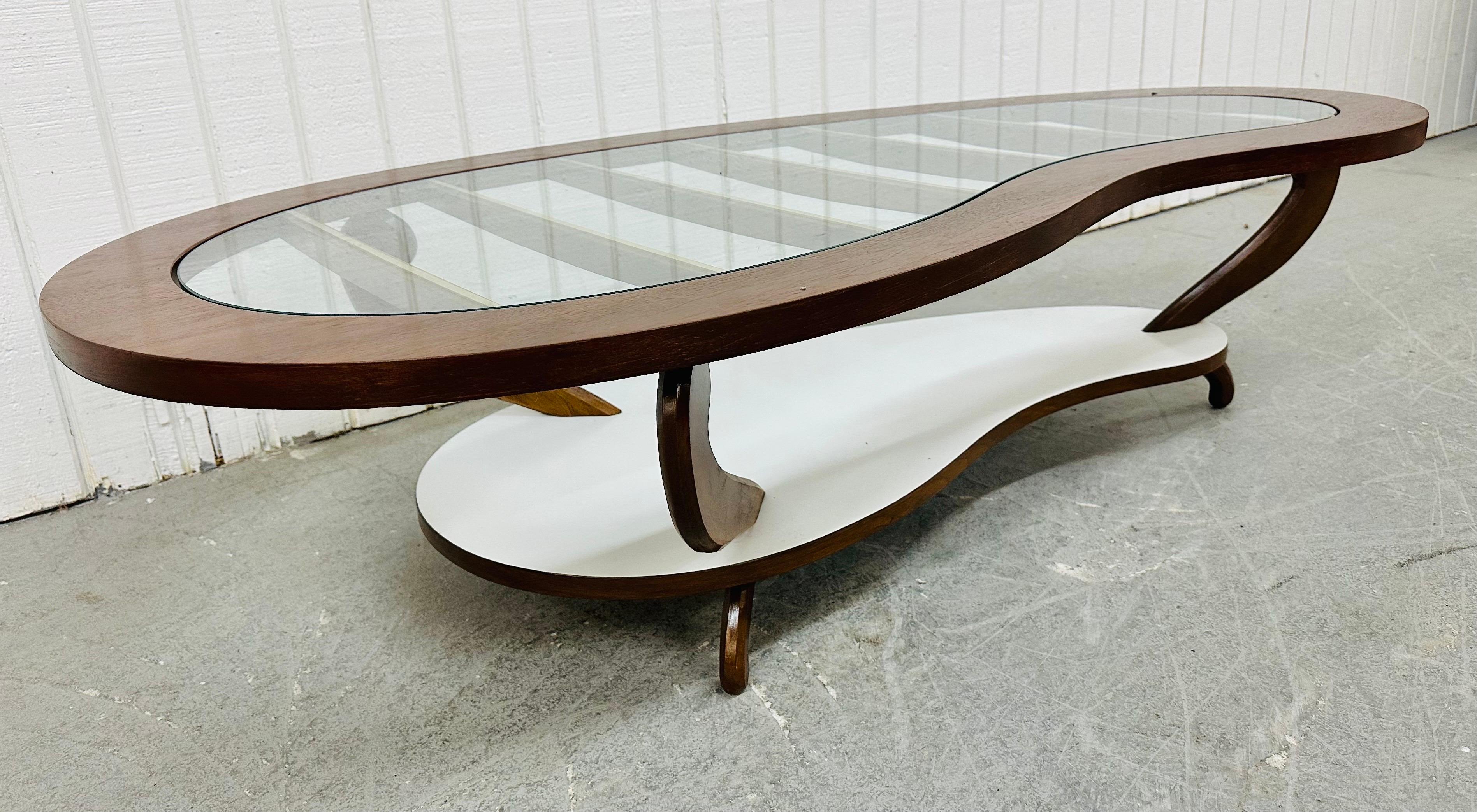 This listing is for a Mid-Century Modern Walnut Kidney Shaped Coffee Table. Featuring a walnut frame, partial glass top with wooden/brass supports, white laminated bottom tier, and modern legs. This is an exceptional combination of quality and