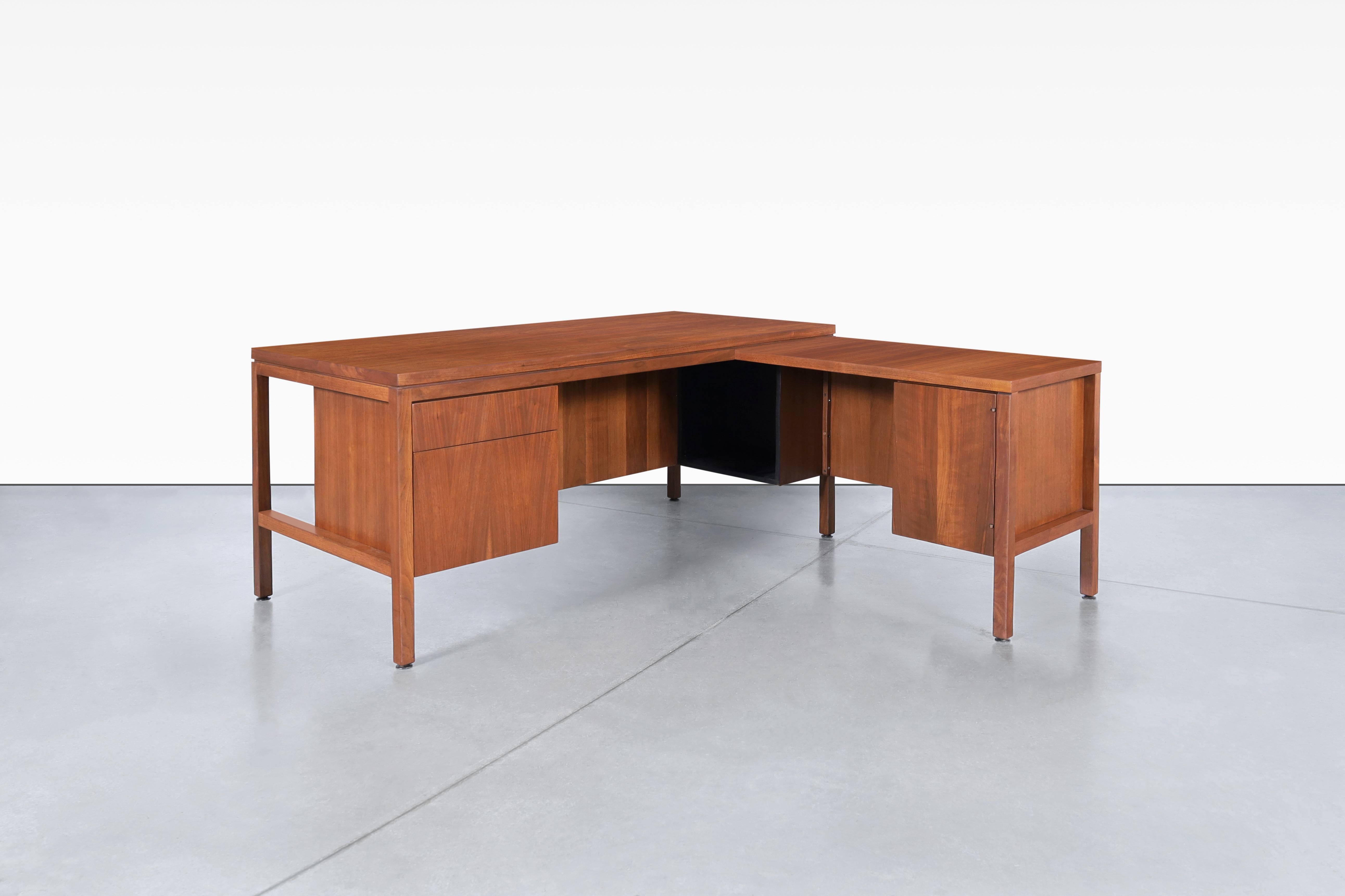 Introducing a stunning mid-century walnut L-shaped desk from the 1960s, a true classic of American design, built to stand the test of time. This desk features a thoughtfully designed layout, with one convenient pull-out drawer, a spacious file