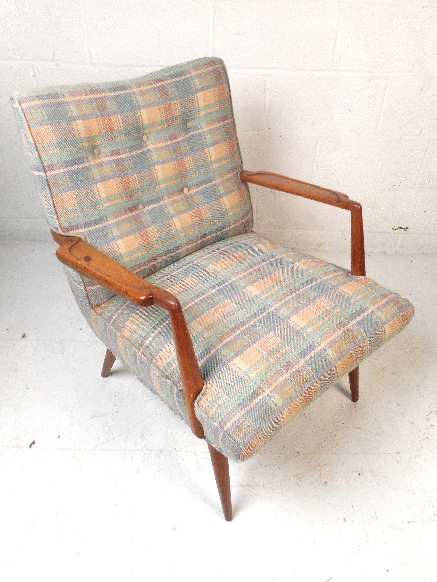 This stylish midcentury lounge chair features vintage plaid upholstery, a tufted backrest, a padded seat cushion ensuring comfort, a well-crafted walnut frame, and splayed back legs providing the chair with an interesting profile. Please confirm