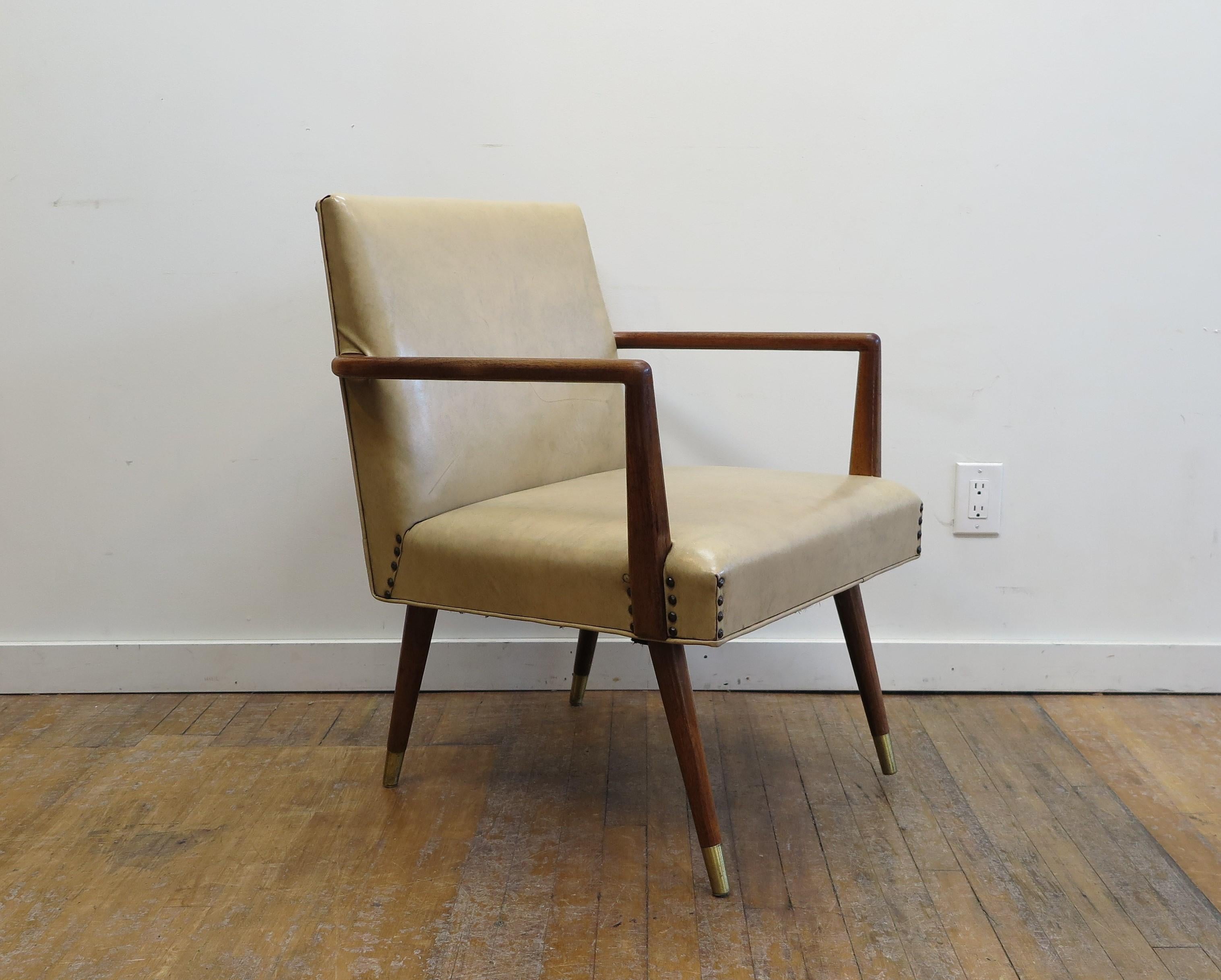 Mid-Century Modern lounge chair. Modernist wooden armed lounge chair in the style of T.H. Robsjohn Gibbings. Walnut frame with Naugahyde covering detailed with nail heads studs and brass sabot feet. Comfortable in good condition all original. Early
