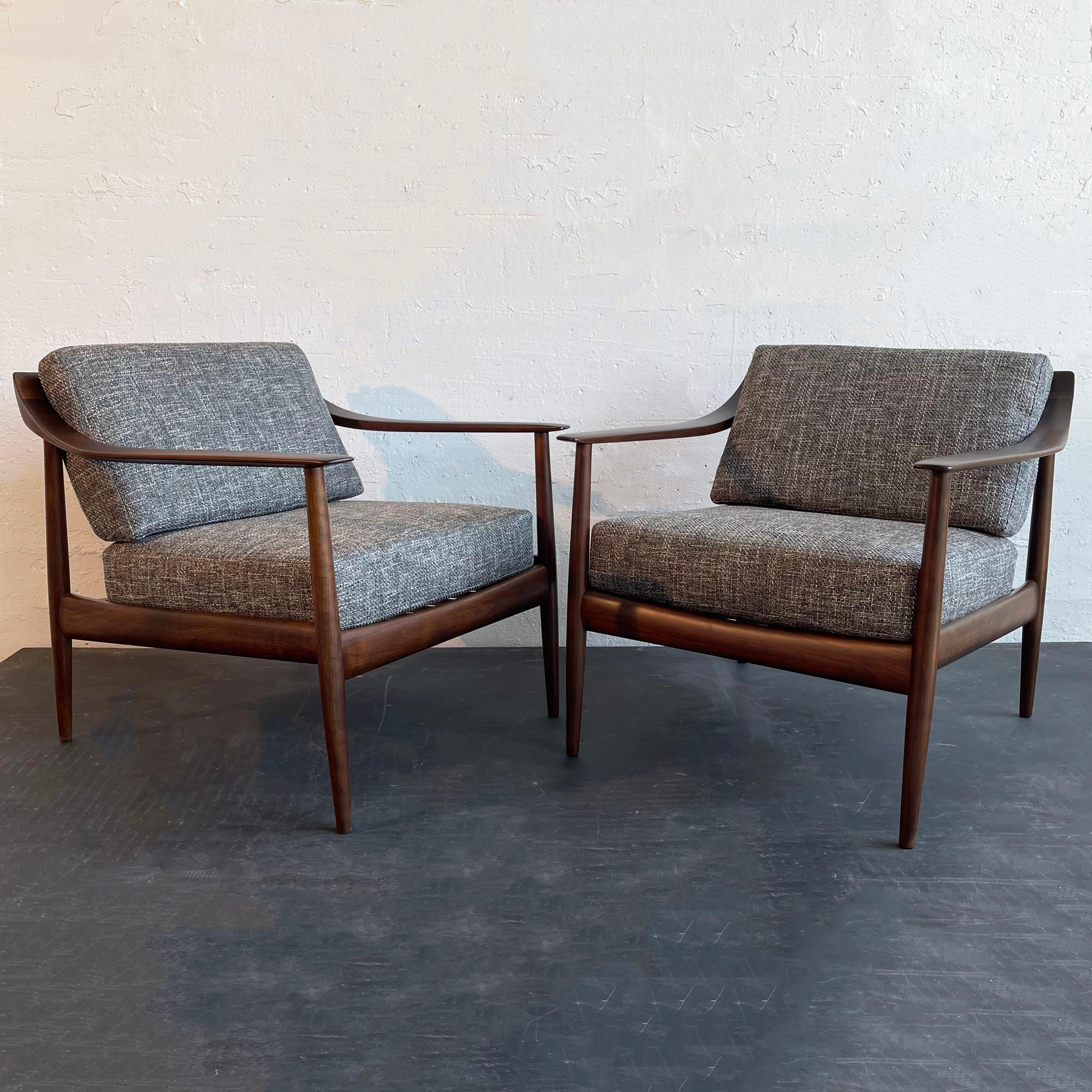 Pair of refined, mid-century modern, Knoll Antimott lounge chairs by German manufacturer Walter Knoll, father of Hans Knoll, founder of Knoll Inc. The chairs feature sleek, minimal walnut frames with sculpted, scoop arms. The seat and back cushions