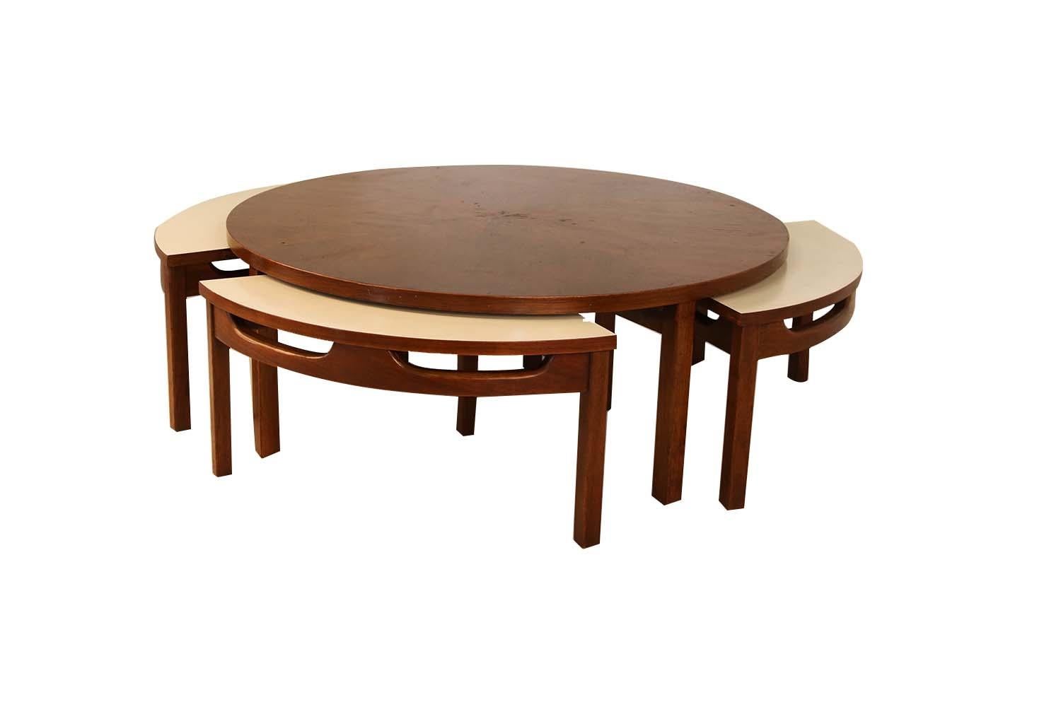 This impressive Mid-Century Modern walnut round coffee table includes four white laminate/walnut nesting tables. This rare coffee table features a book-matched heartwood walnut veneer top resting on four strong angular walnut legs. The four pie