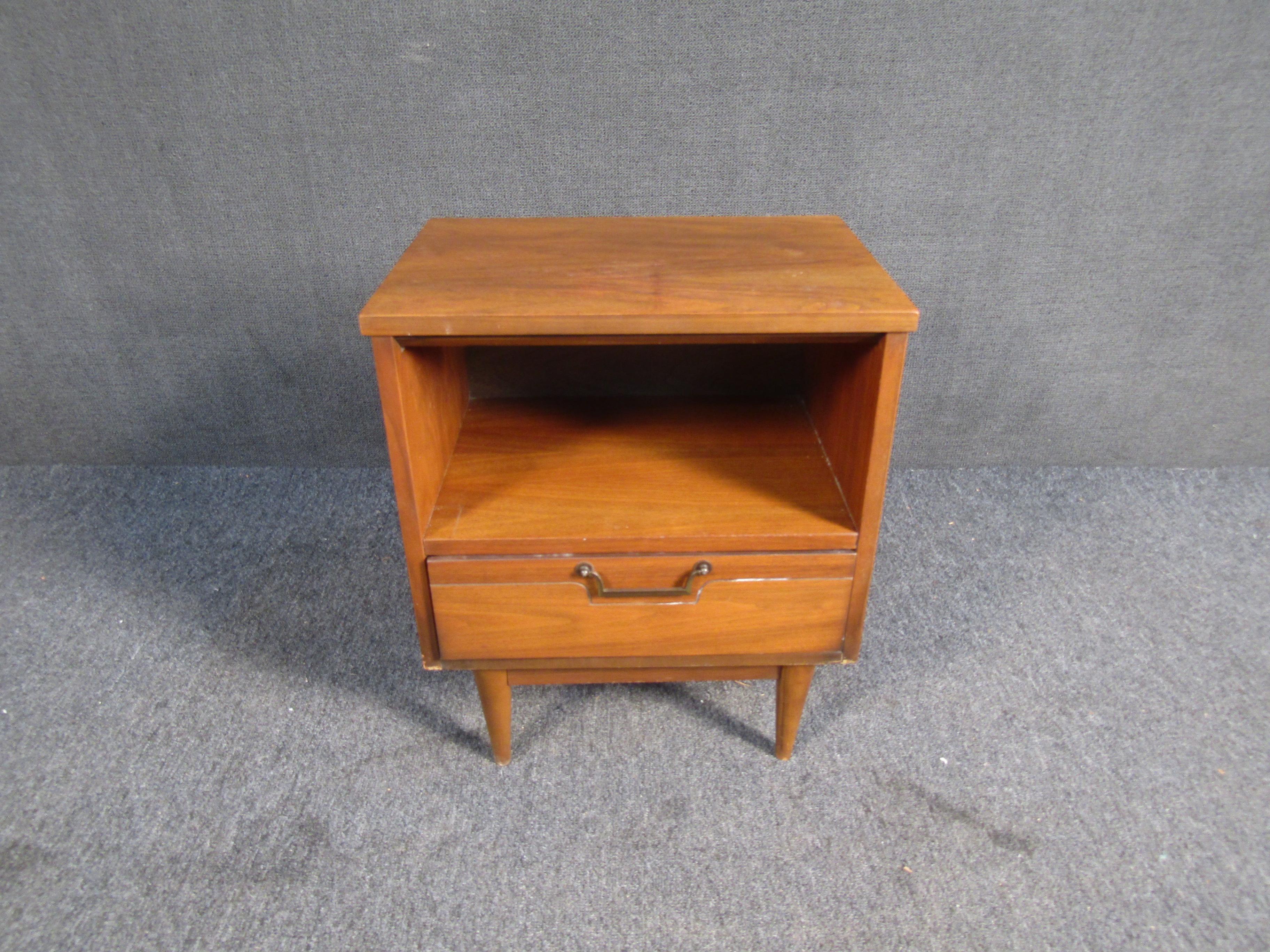 ( 1 ) Mid-Century Modern walnut nightstand in walnut. This nightstand features an all wood construction, tapered legs, brass handle and one drawer. A perfect end table for a small space in need of a place to put a lamp, drink, magazines or odds and