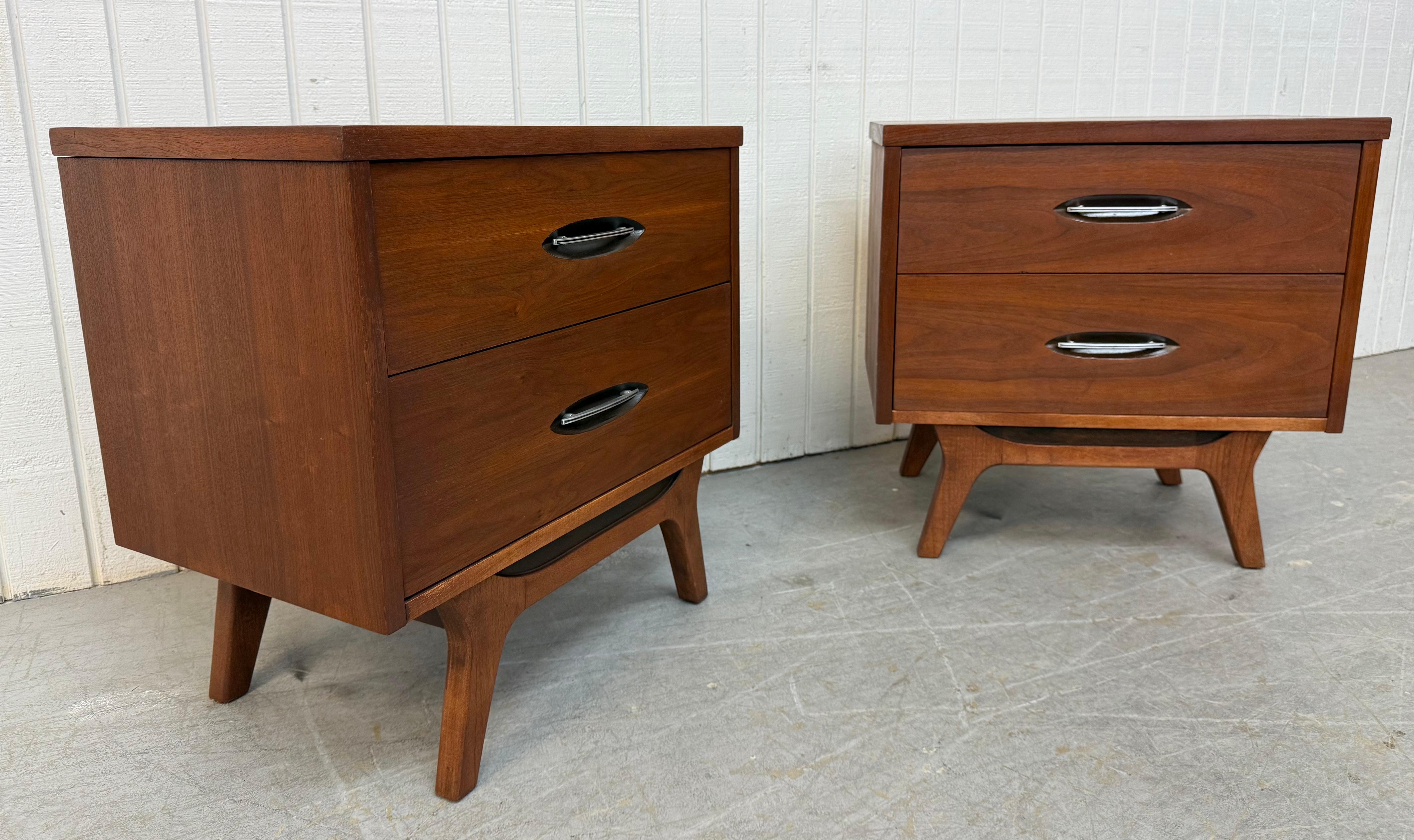 Cette annonce concerne une paire de tables de nuit en noyer de style moderne du milieu du siècle. Elle se caractérise par un design rectiligne, deux tiroirs de rangement, une quincaillerie chromée, des pieds modernes avec étirement et une belle