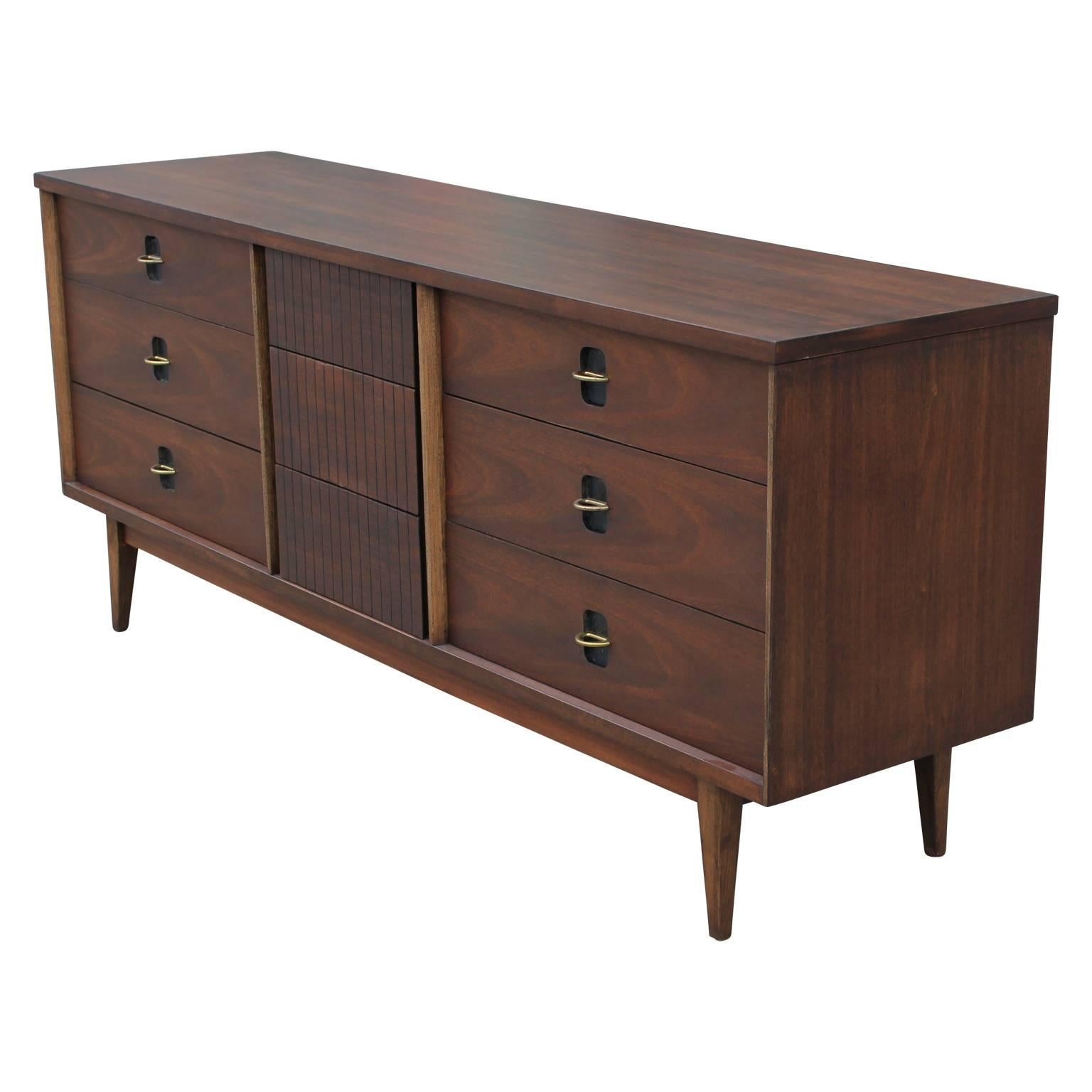 Mid century modern nine drawer dresser made from gorgeous walnut with brass pulls and detailing. In the style of American of Martinsville. The contrast between the brown, black and brass creates a lovely interest. 