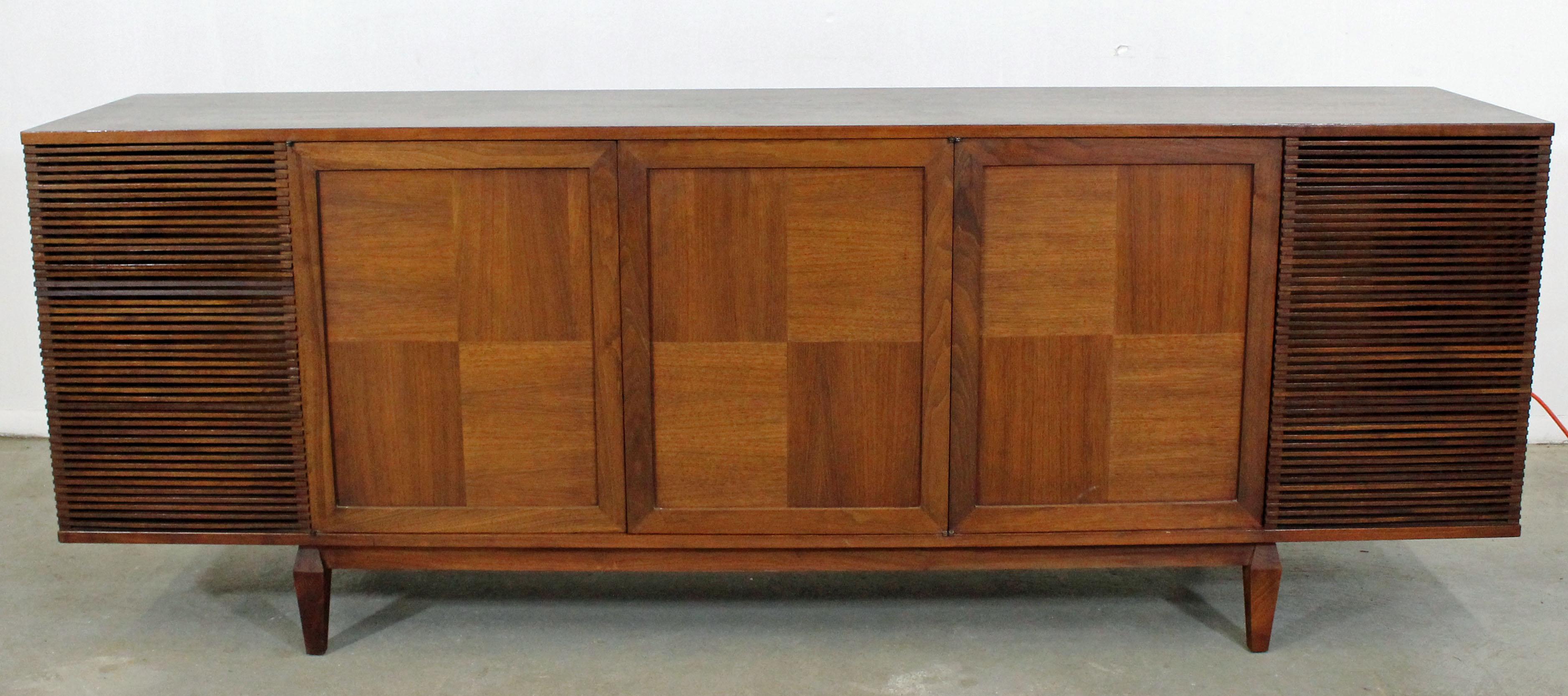 What a find. Offered is a customized credenza, formerly a record player/stereo, that's been turned into a bar cabinet. Features three doors with push latches that open up to a inside shelving and storage space with two empty cavities on each side