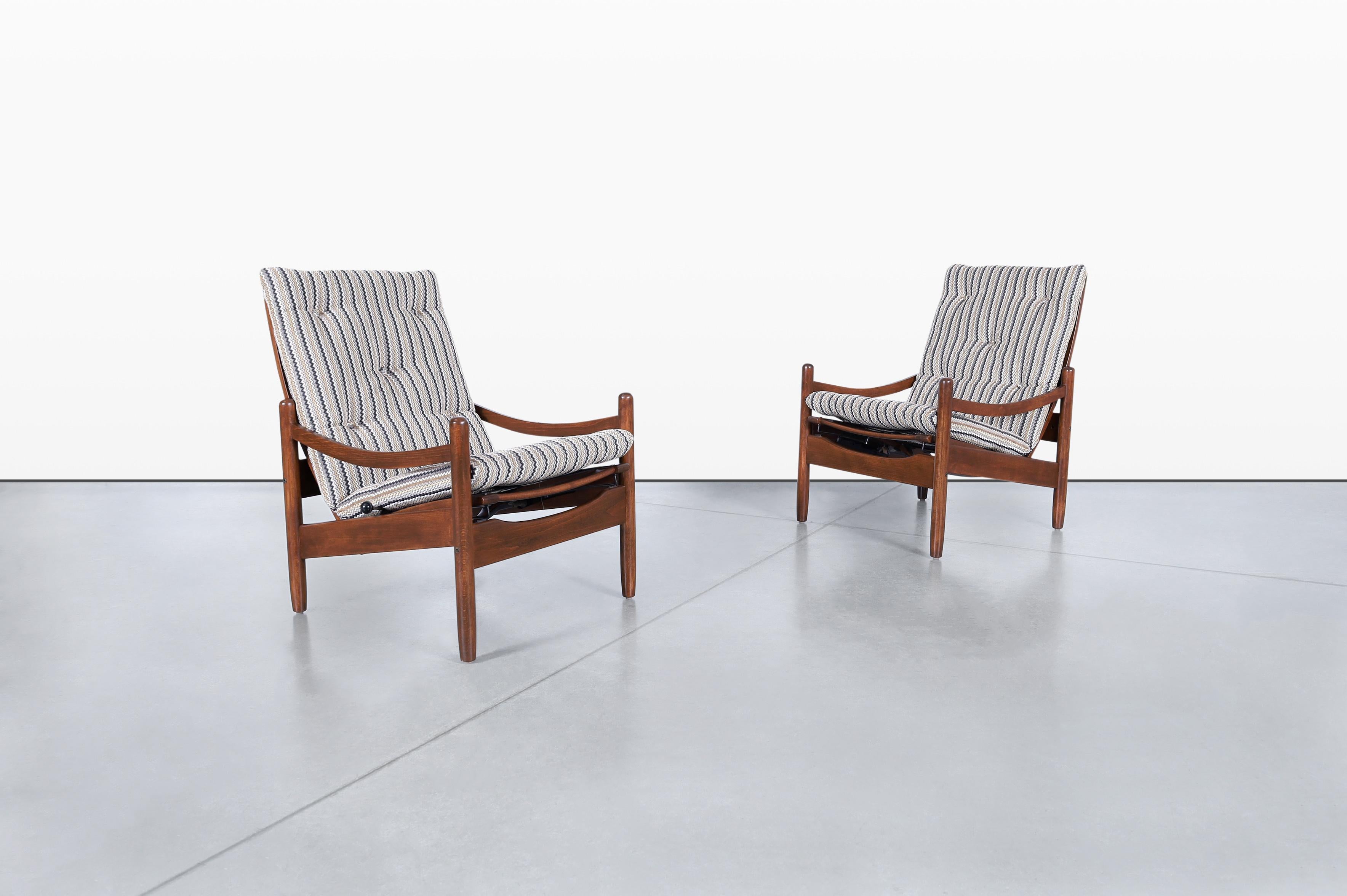 Descubre la elegancia del diseño moderno de mediados de siglo con estos exquisitos sillones reclinables de nogal, fabricados en Estados Unidos durante la década de 1960. Con un armazón de nogal bellamente teñido, estas sillas son un verdadero alarde