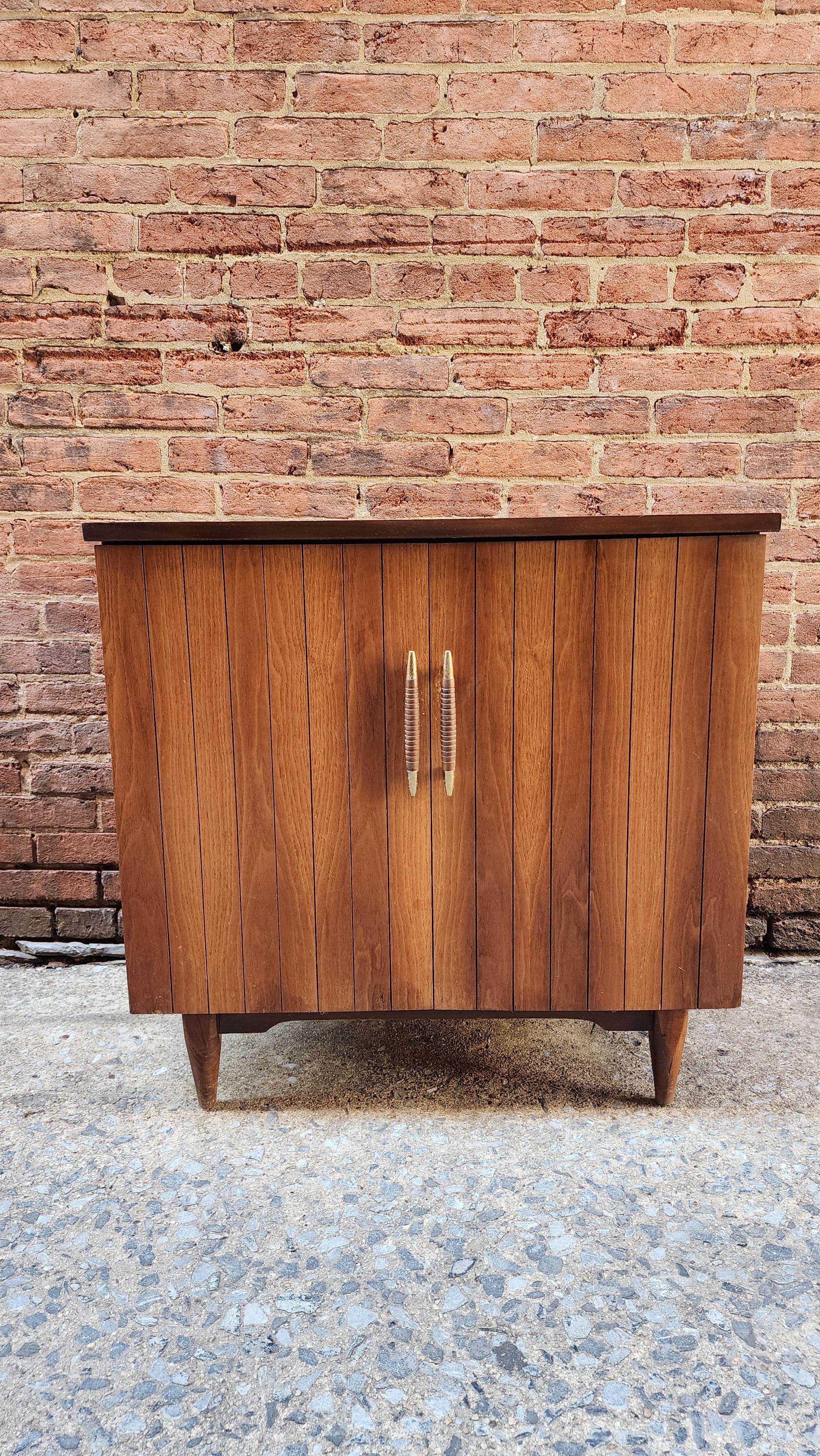 This walnut Mid-Century modern record cabinet is in the iconic style of the 1950s and 60s. The beautiful grain on the doors had been restored and enhanced to show off the beauty of the wood. Behind the doors is a divided space for your record
