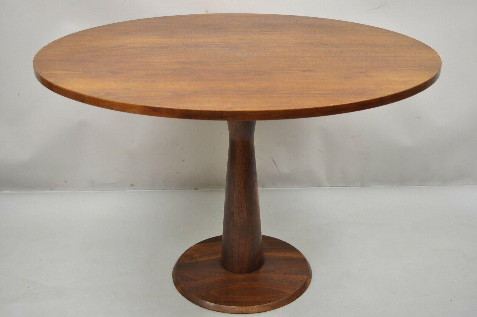 Mid-Century Modern walnut round dining table with hourglass pedestal base. Item features an hourglass shaped pedestal base, 42