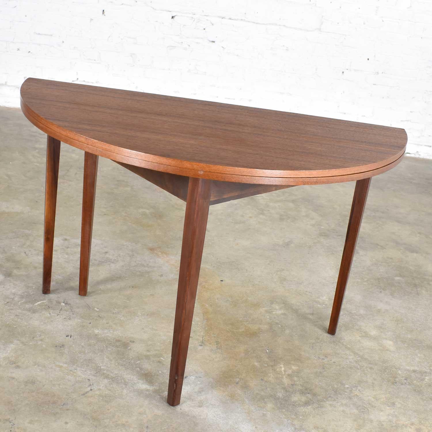 Handsome Mid-Century Modern round dining table with a flip top or folding top converting it to a demilune half round table. It is in fabulous vintage condition. The original finish has been restored however there may still be small signs of age and